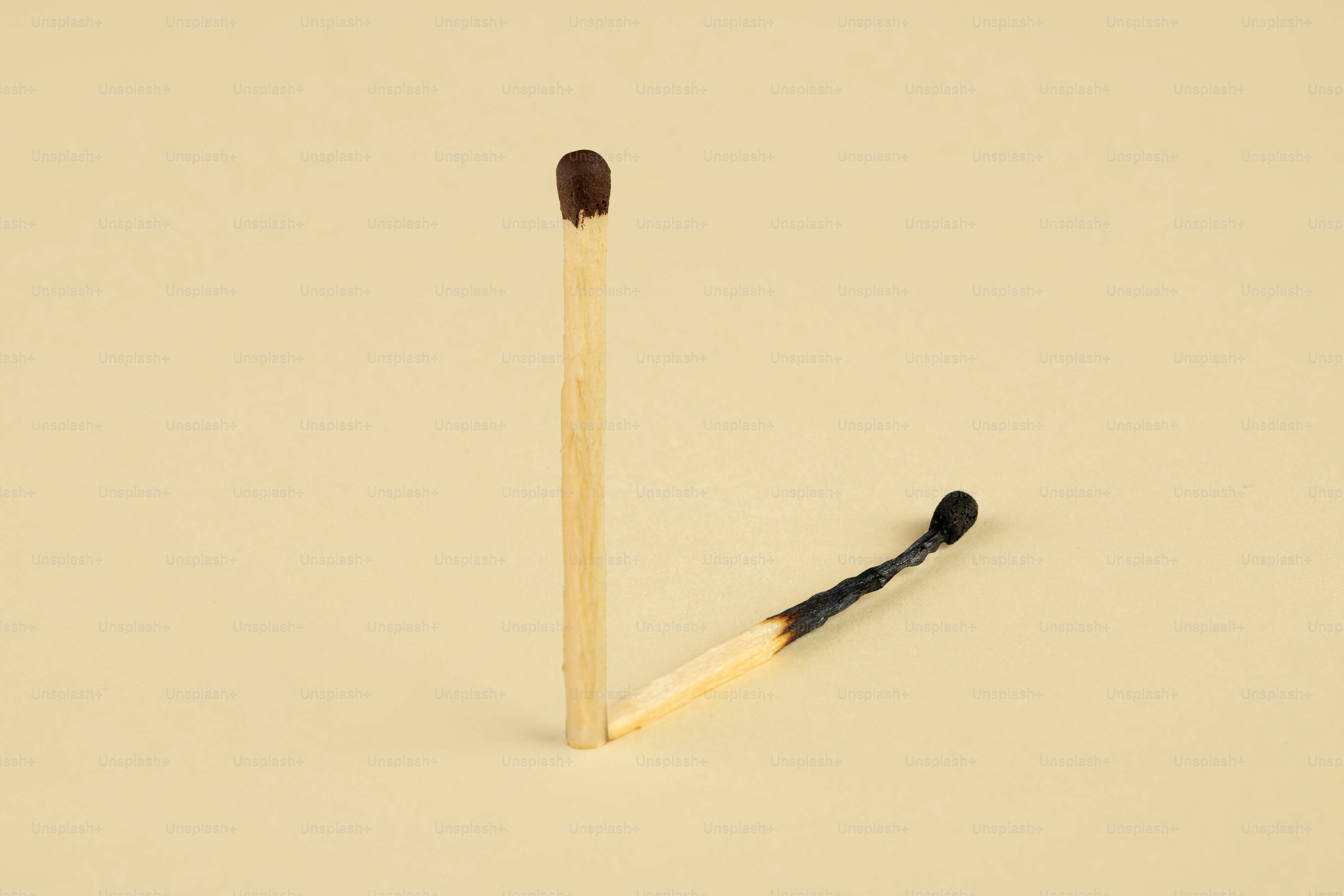 One unlit match next to a burnt match.