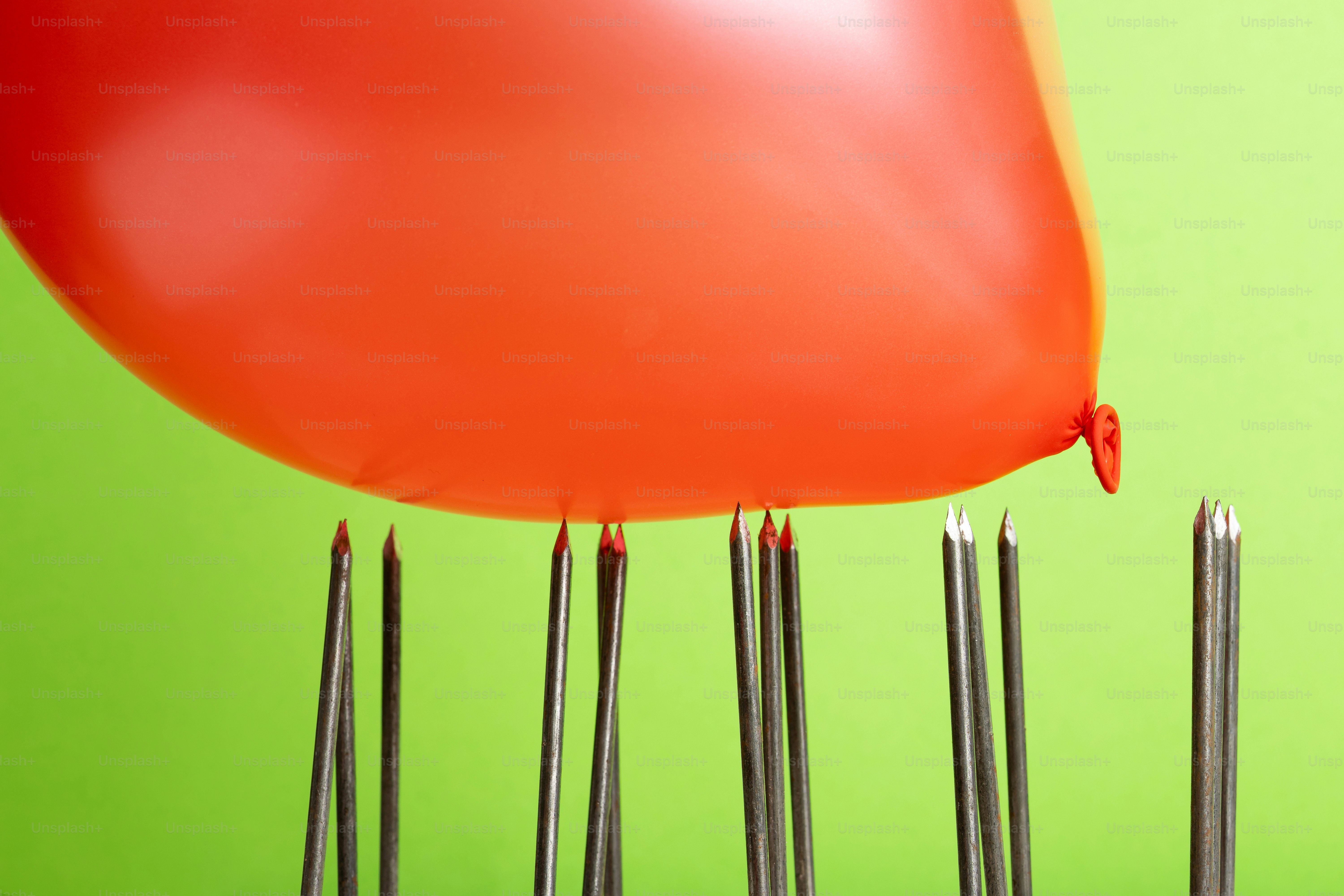 Red balloon hovering over sharp needles