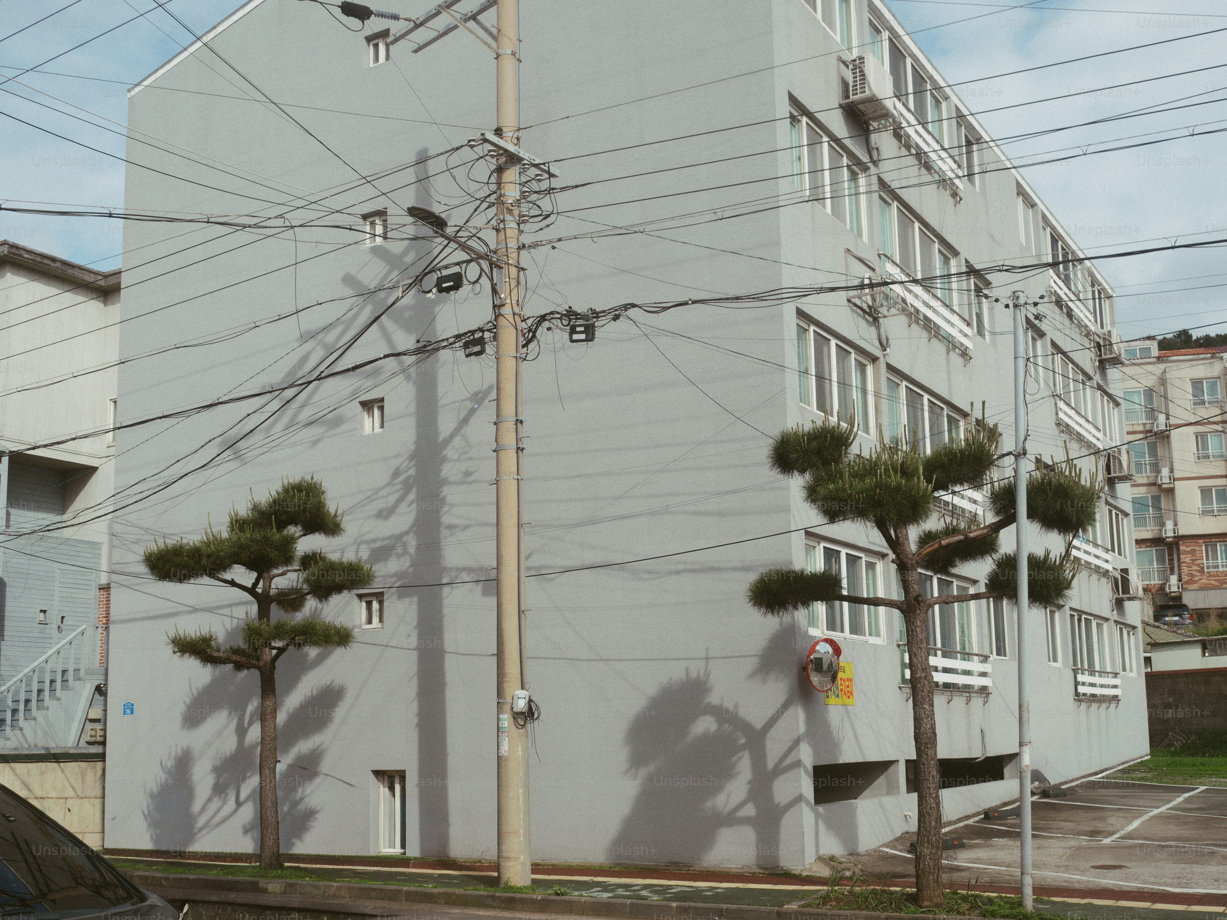Gray apartment building with trees and power lines.