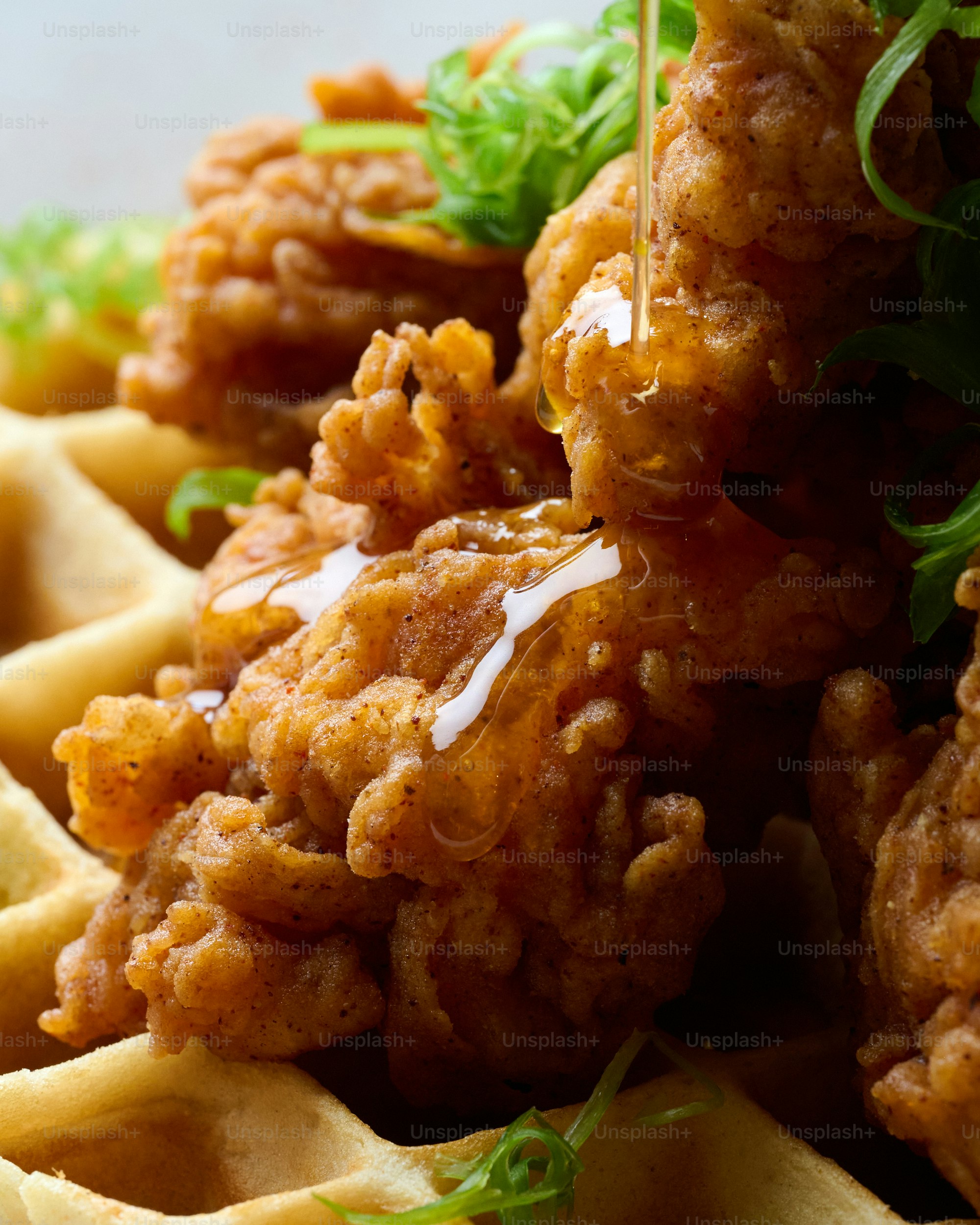 Ayam goreng renyah ditaburi madu di atas wafel.