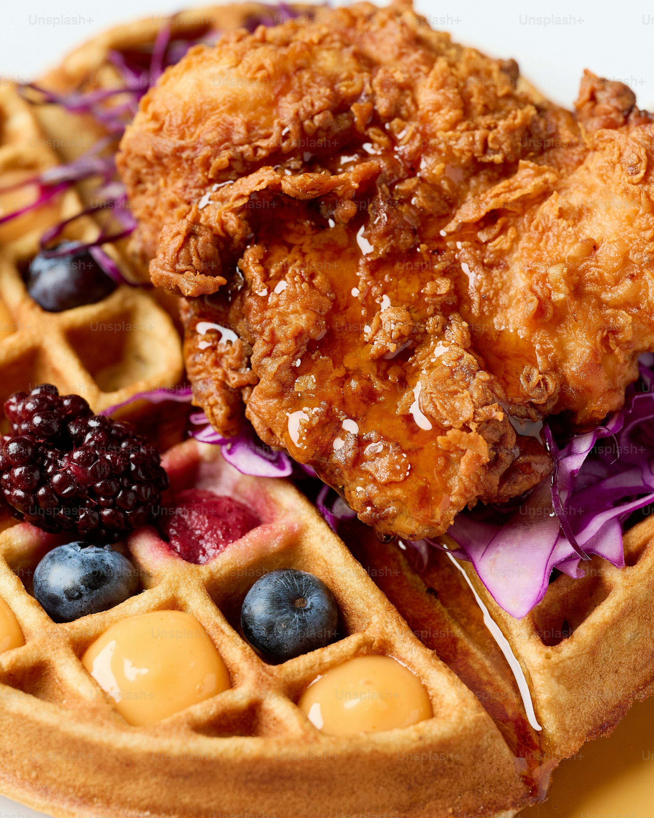 Ayam goreng renyah di atas wafel dengan buah beri dan sirup