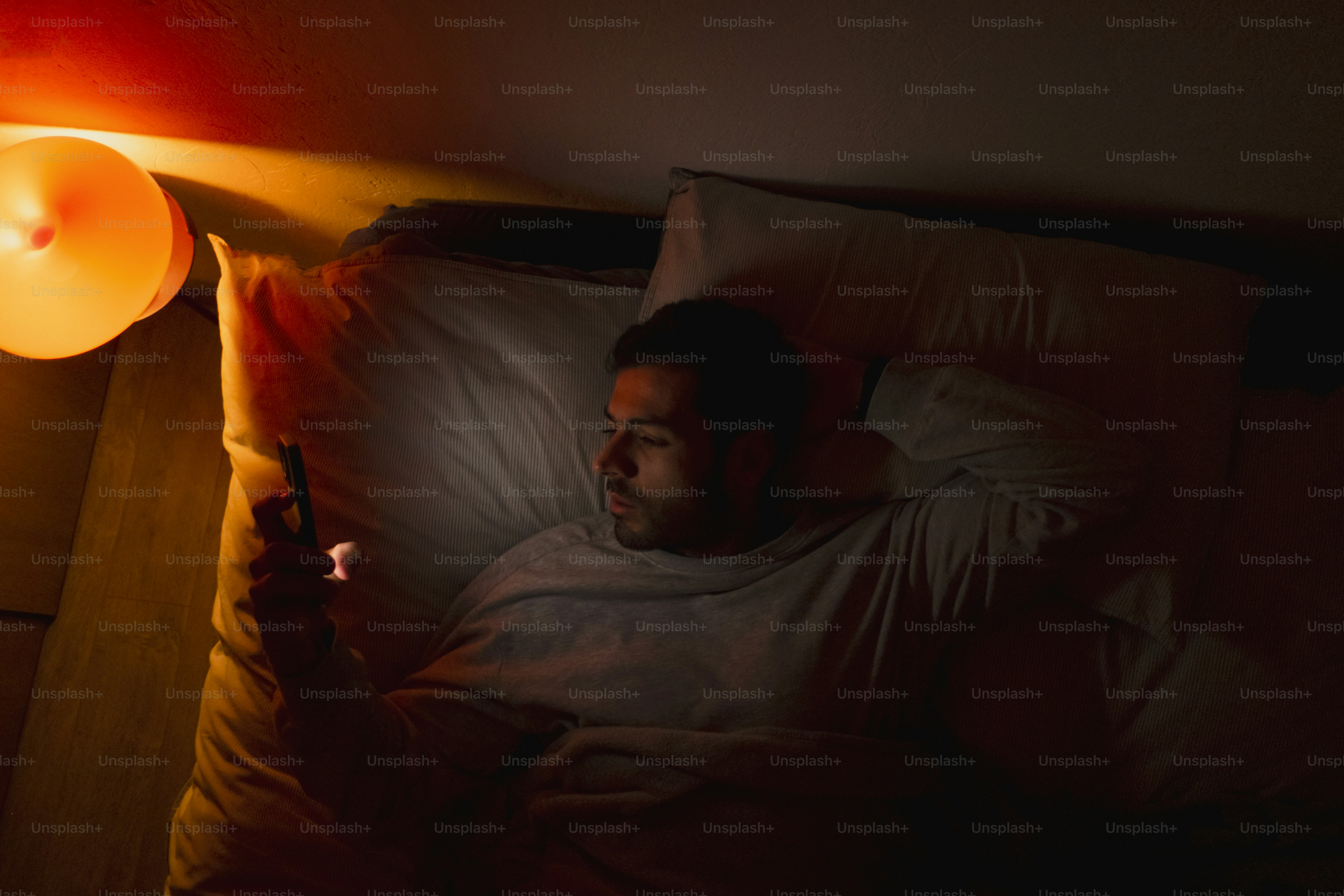Man in bed looking at phone at night