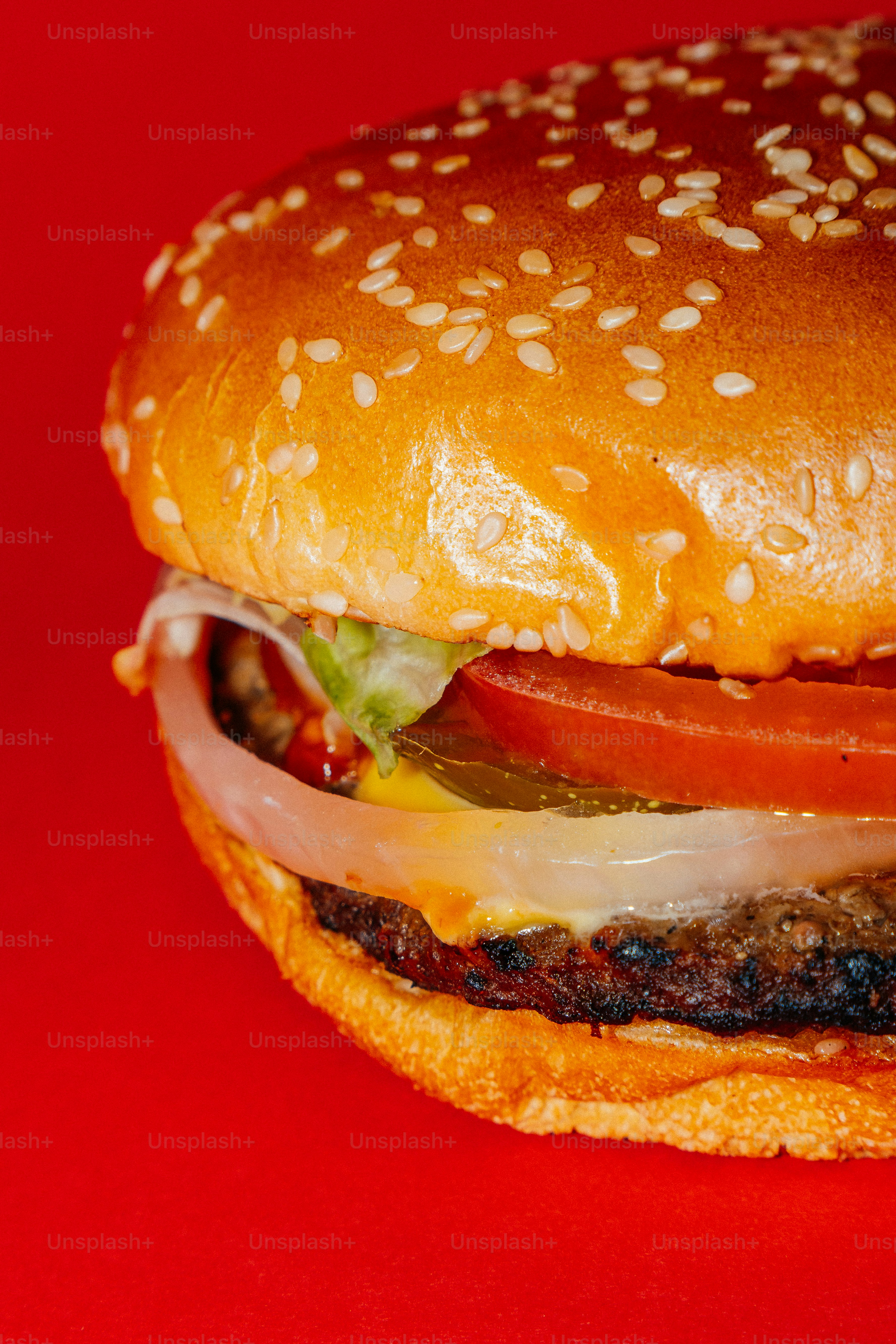 Ein saftiger Hamburger mit Sesambrötchen auf rotem Hintergrund