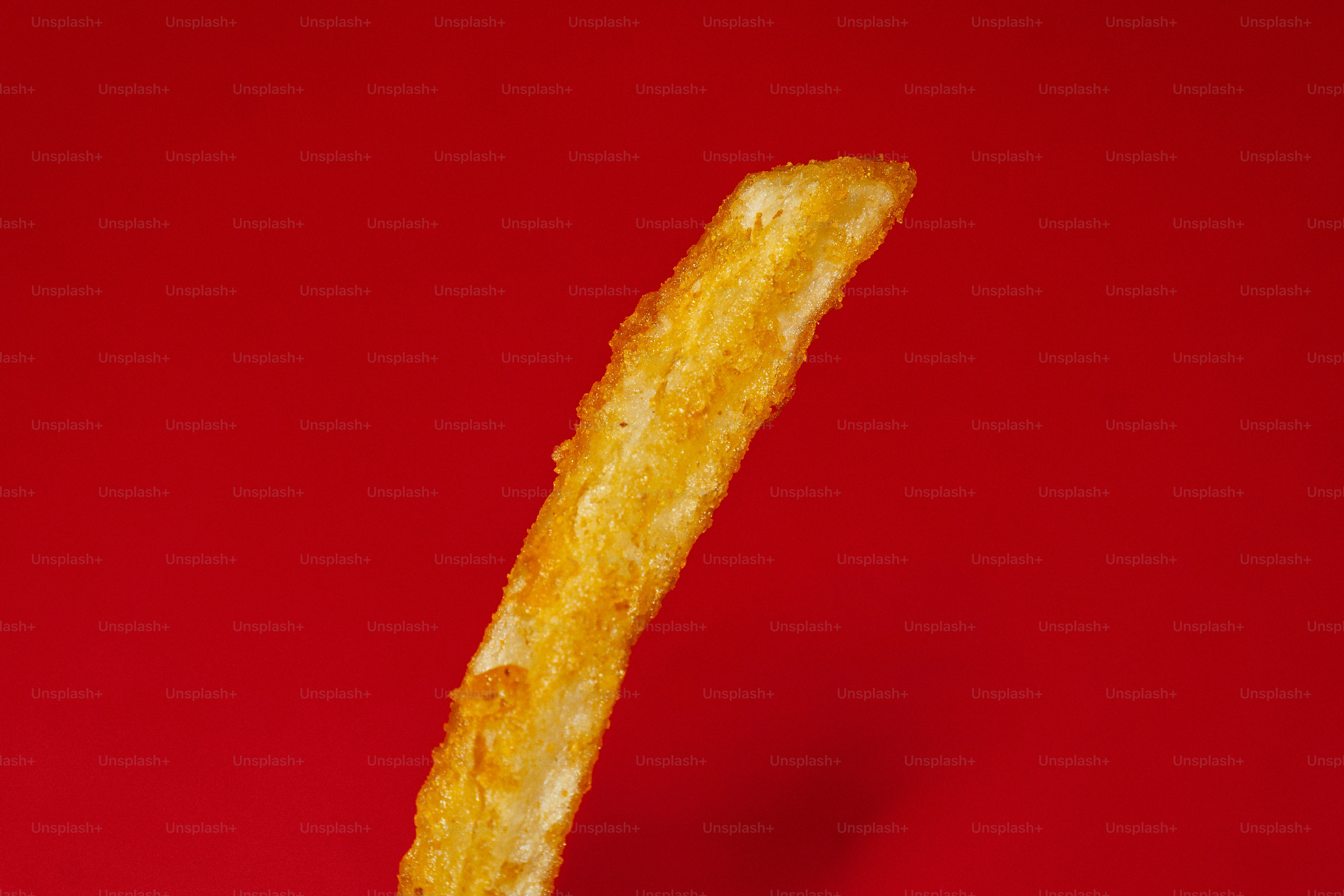 Eine einzelne Pommes auf rotem Hintergrund