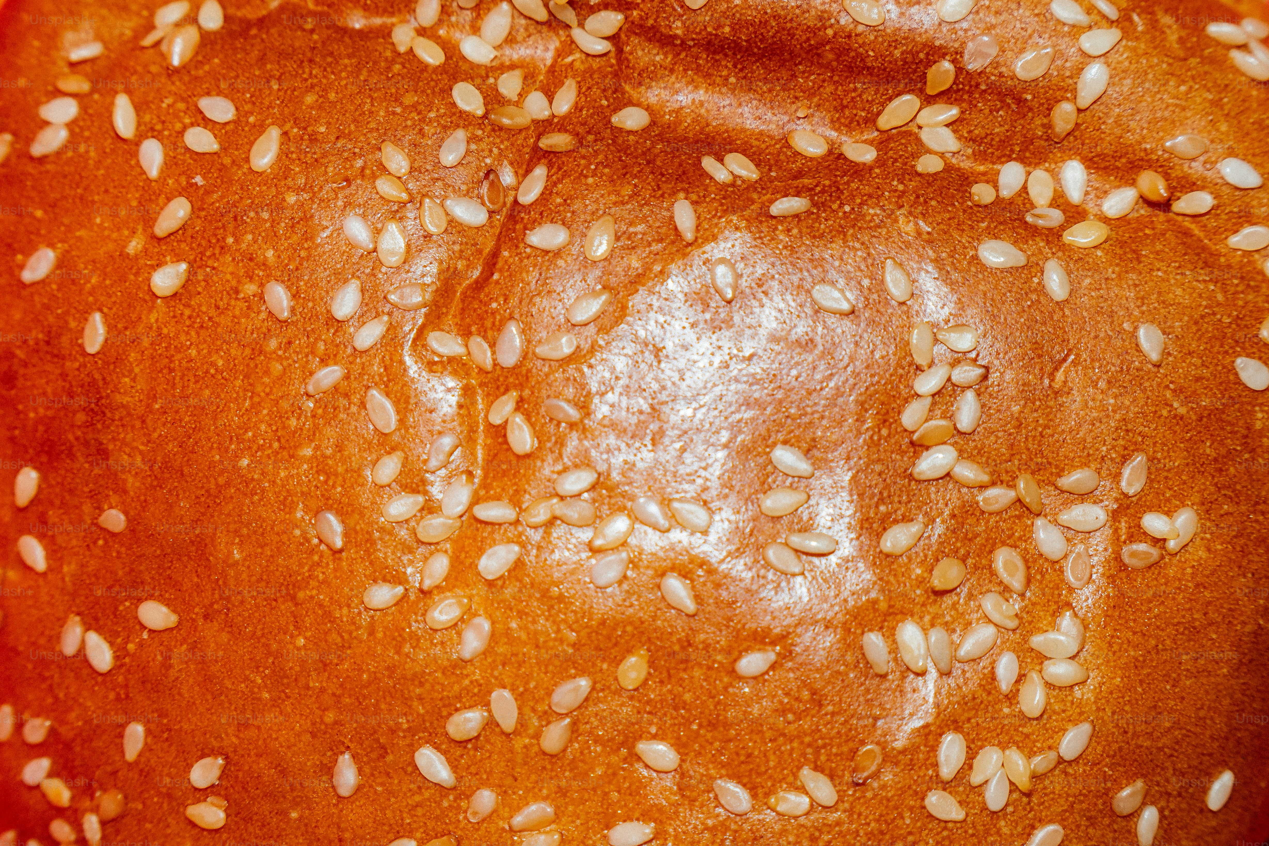 Nahaufnahme eines goldbraunen Hamburgerbrötchens mit Sesamsamen.