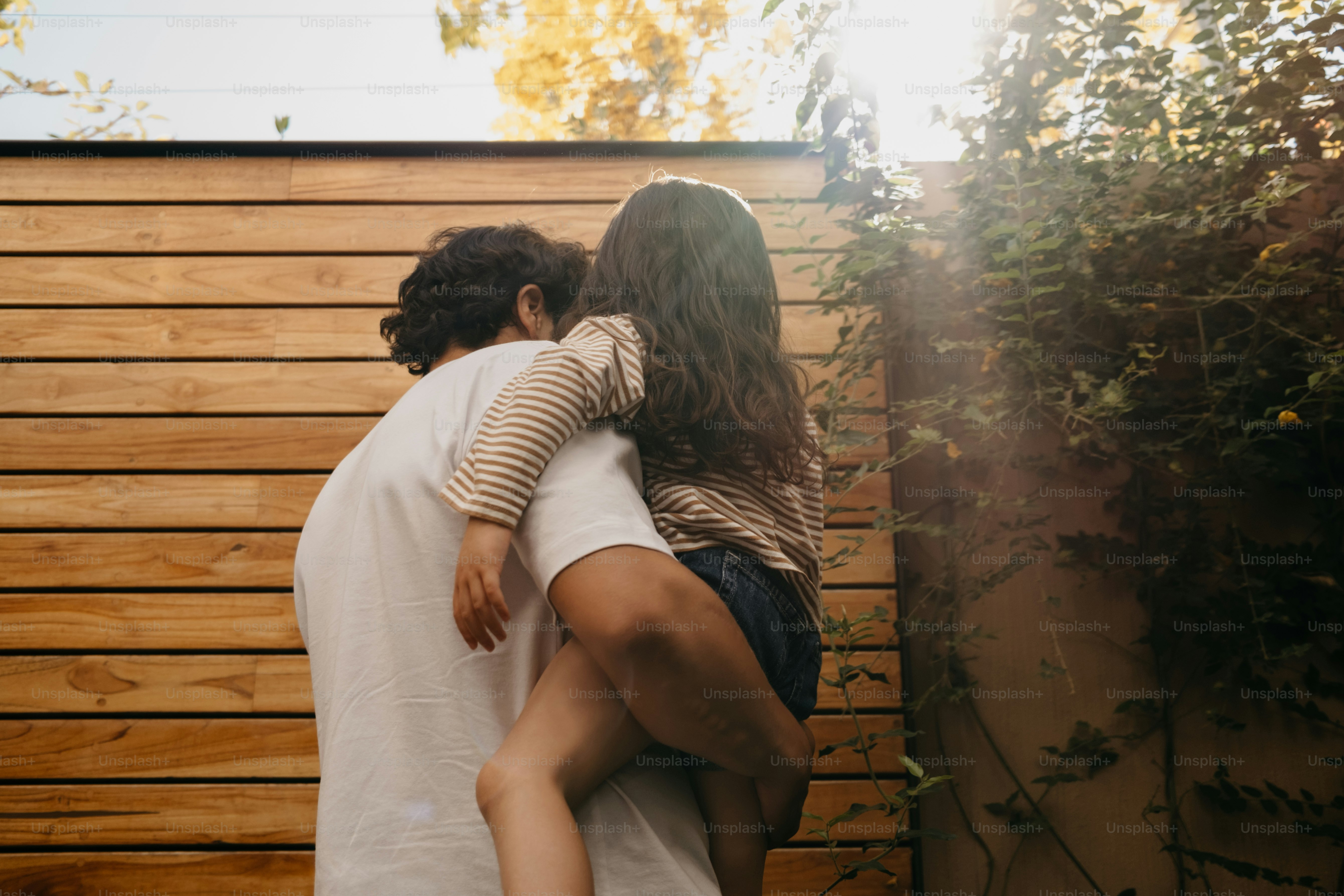 Padre che tiene la figlia vicino a un muro di legno
