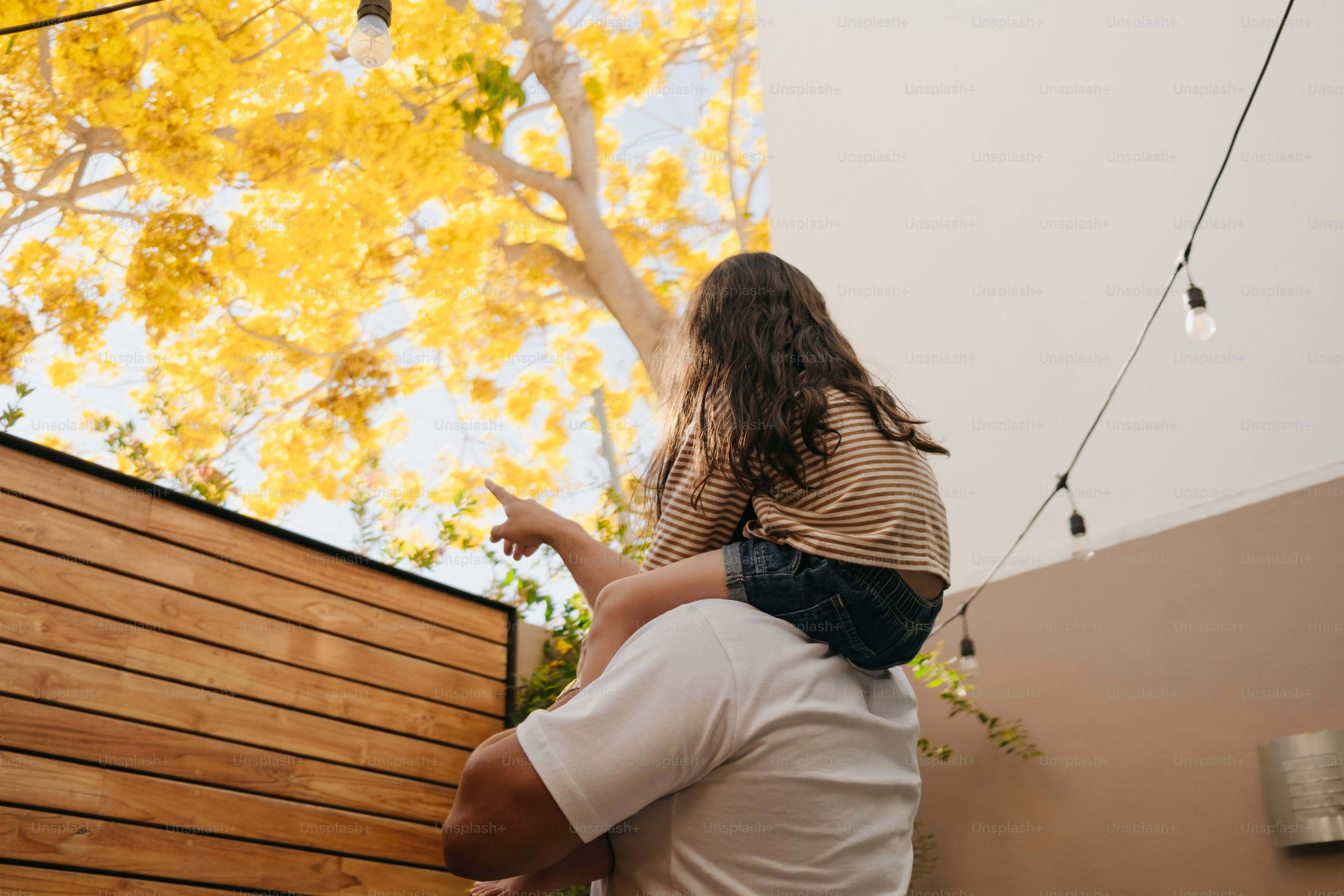 La ragazza sulle spalle indica un albero giallo brillante.