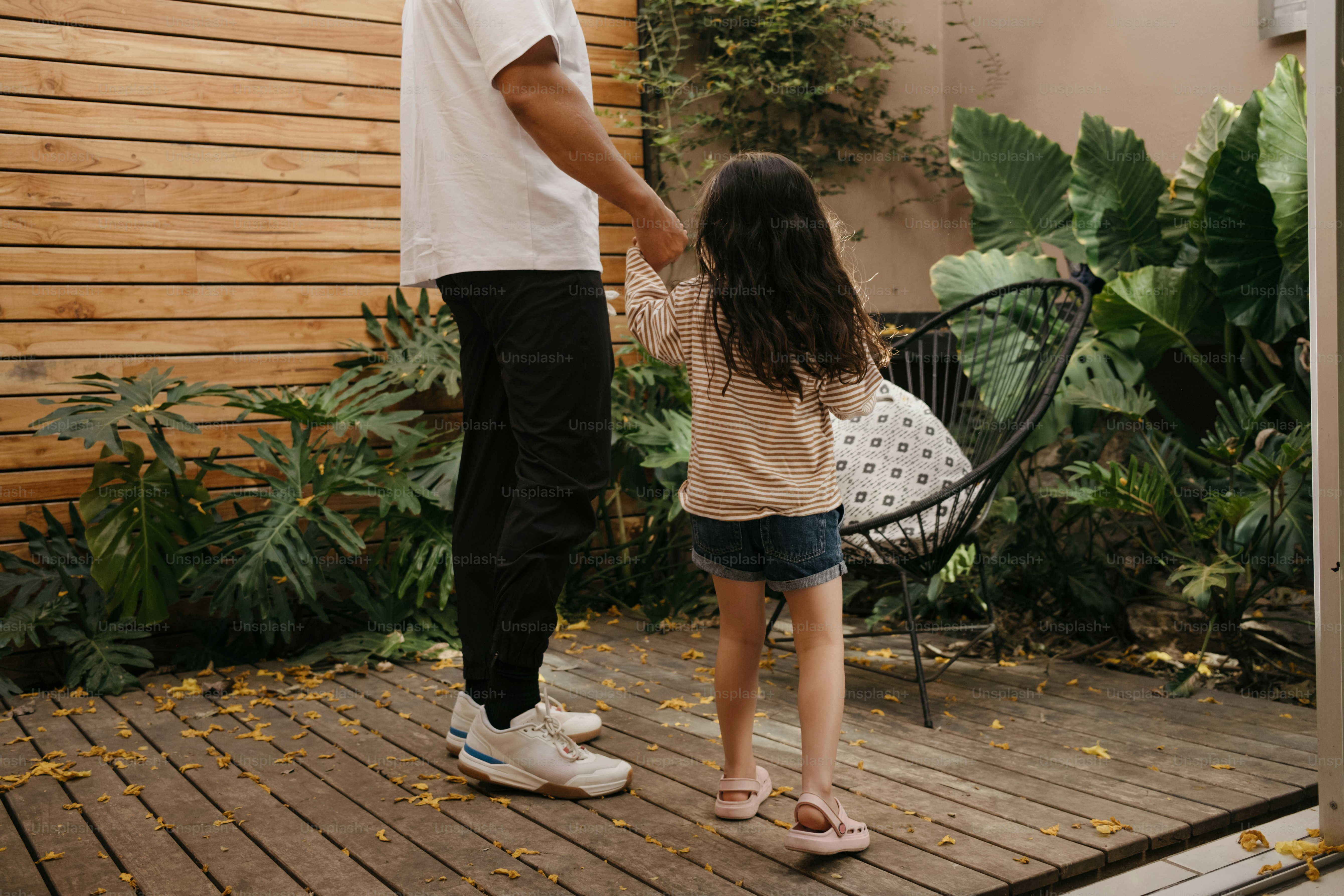 Padre e figlia che si tengono per mano in un giardino.