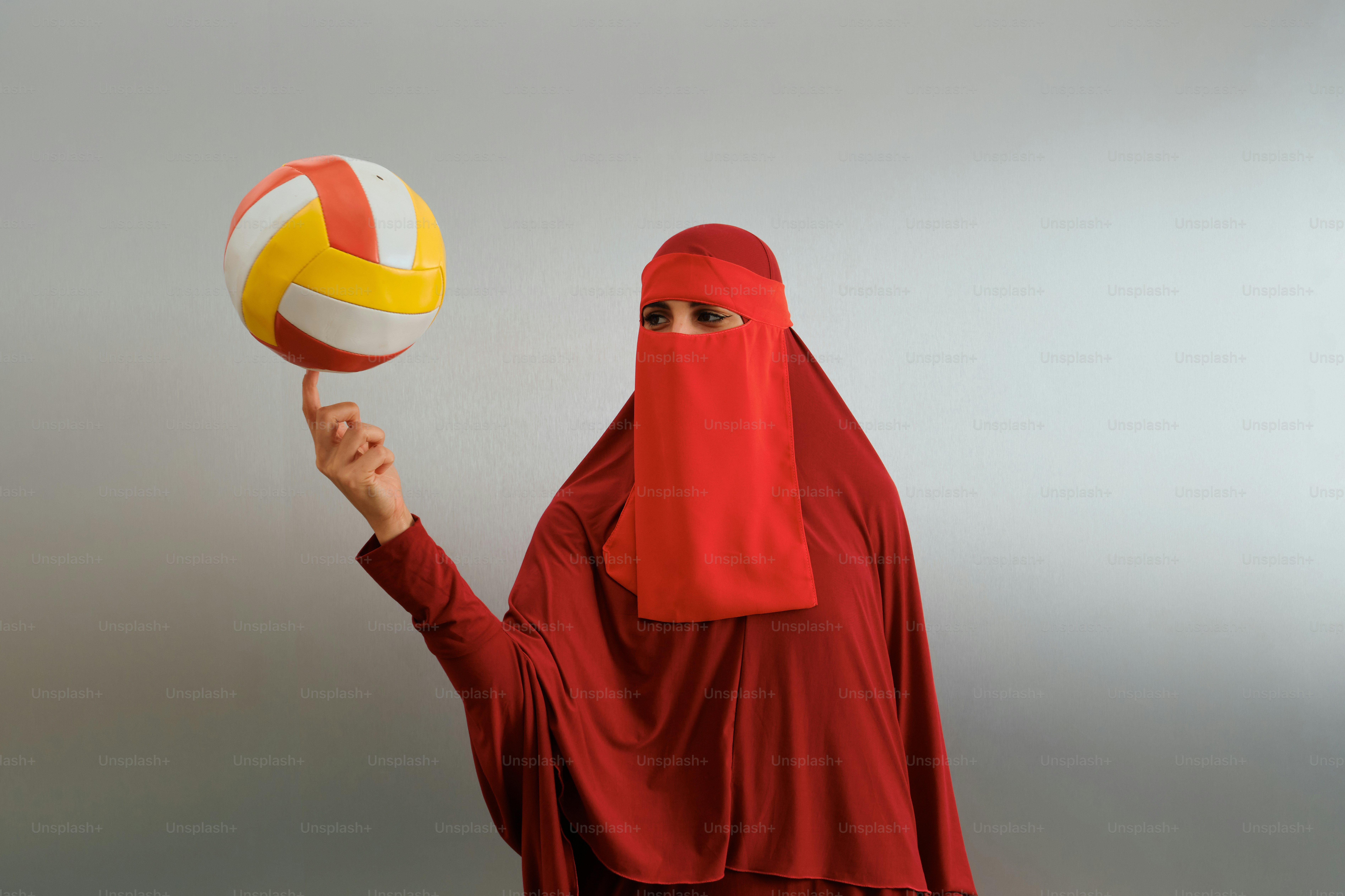 Wanita berhijab merah berputar bola voli di jari