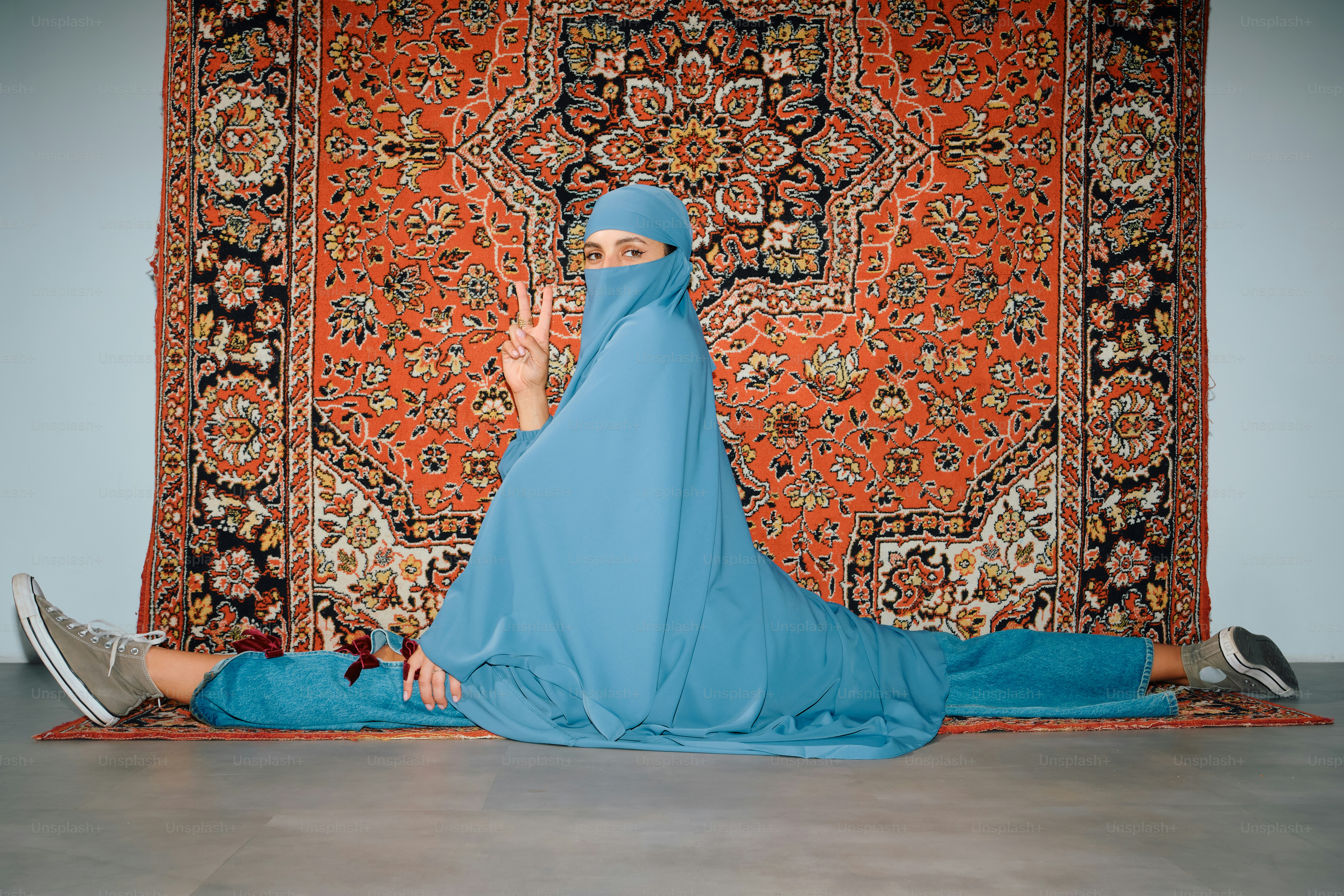 Wanita berhijab biru melakukan split di atas karpet