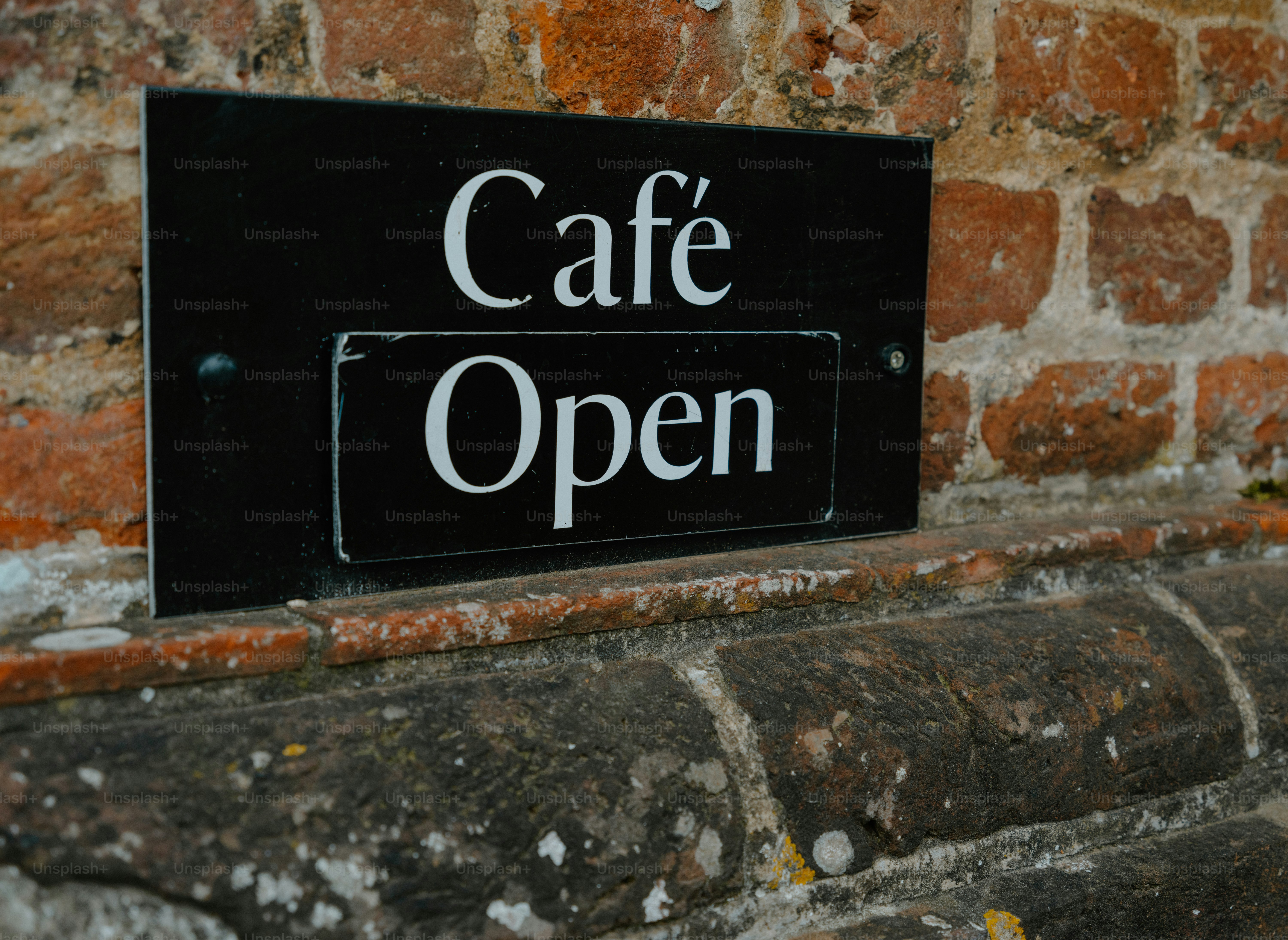 Schwarzes Café-Open-Schild an der Backsteinwand