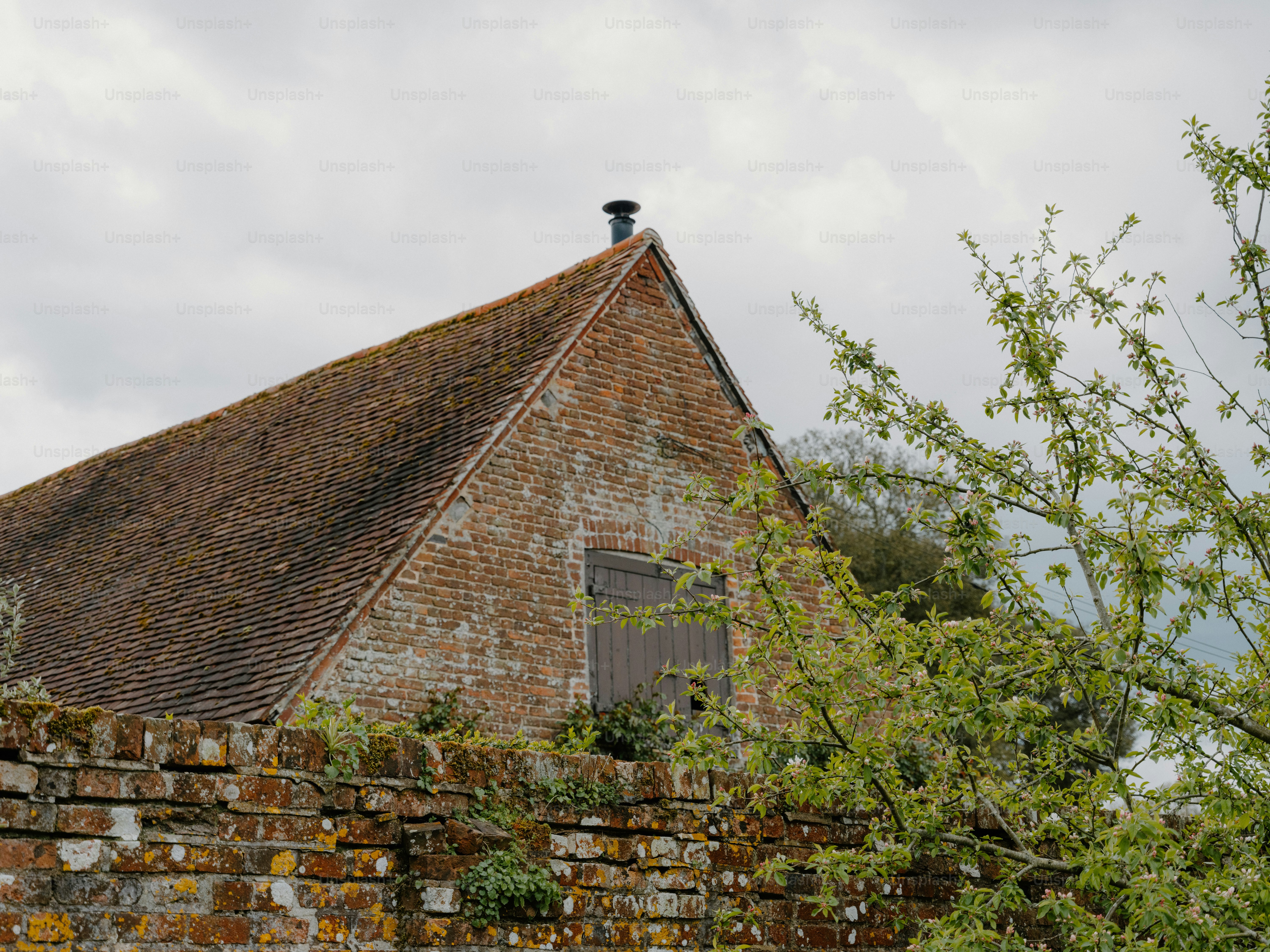 Vieux bâtiment en brique avec un toit en tuiles sous un ciel nuageux