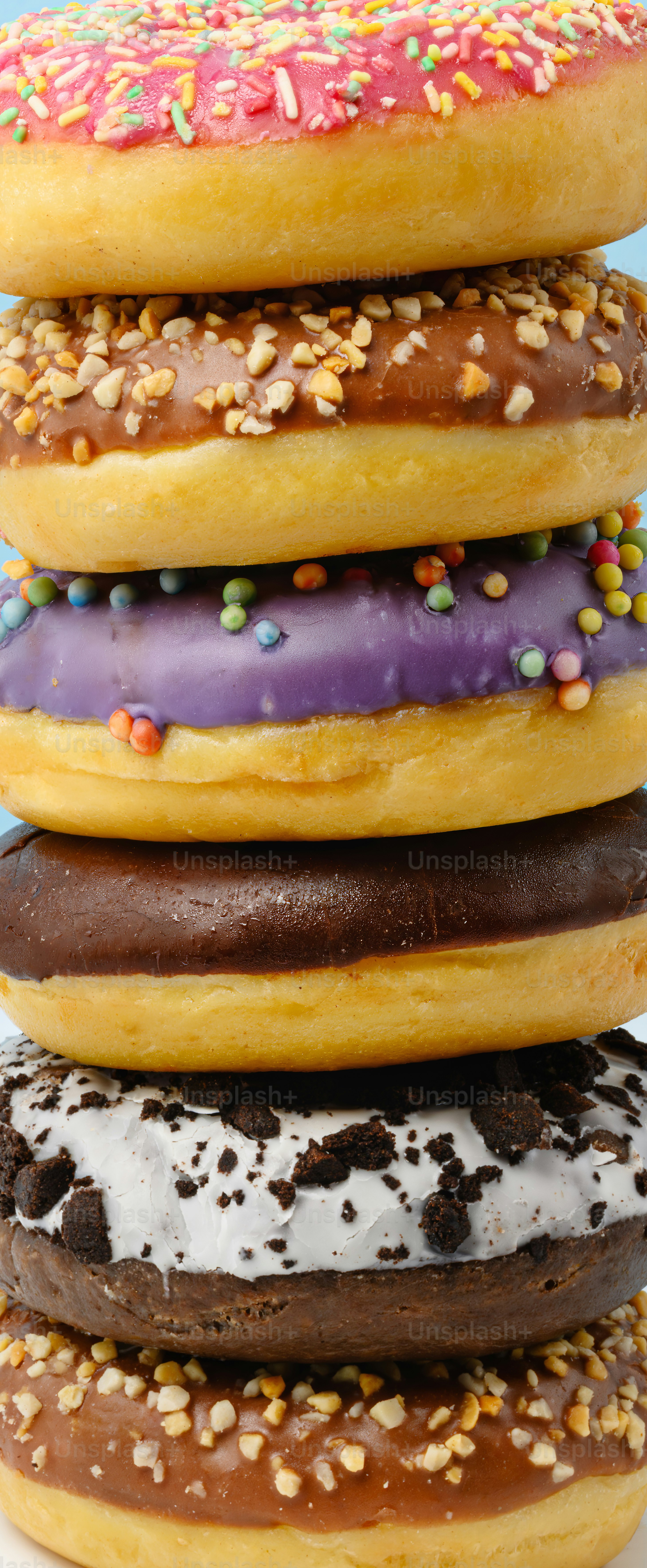 Stapel bunte, glasierte Donuts mit Streuseln und Nüssen