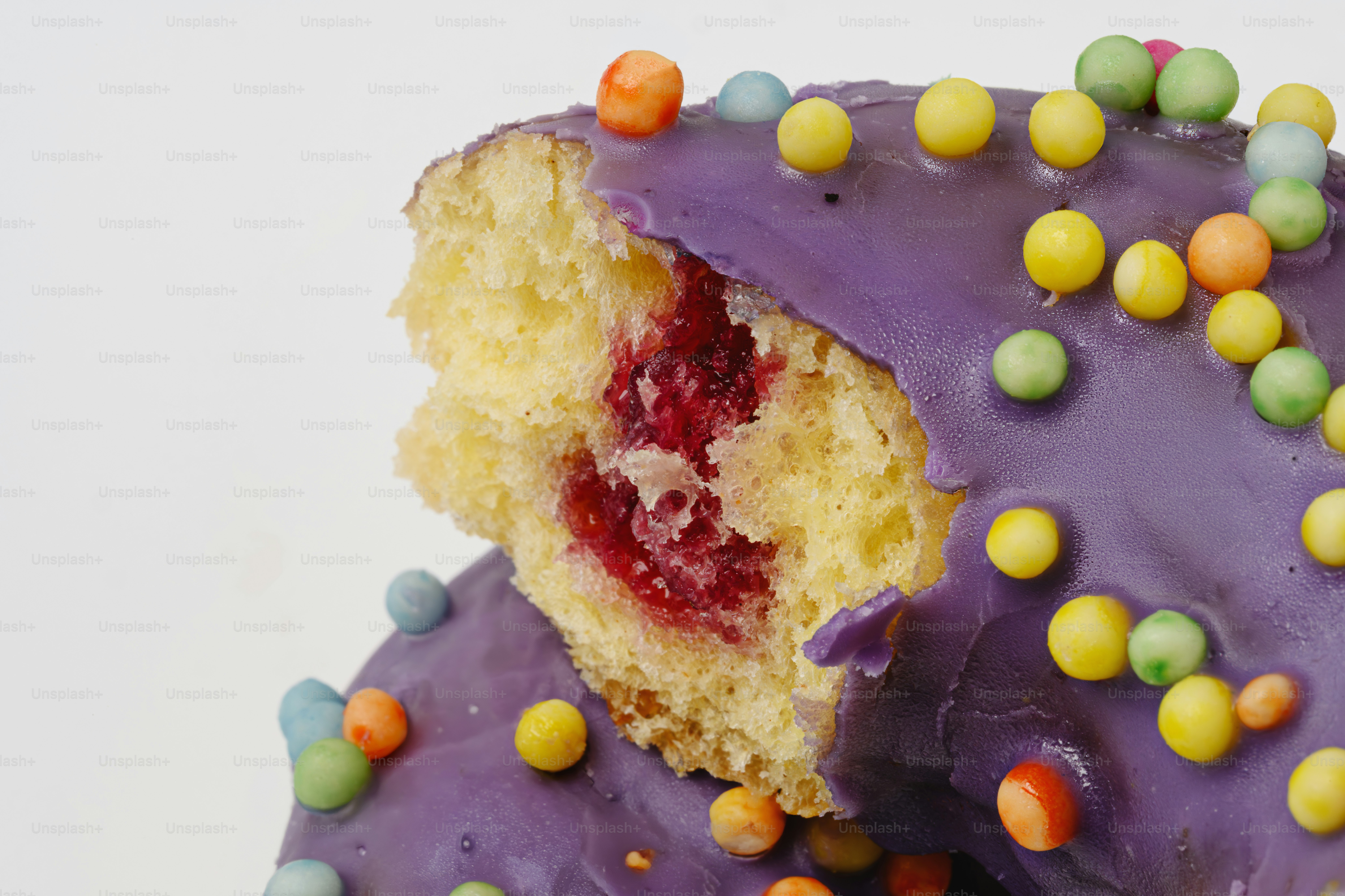 Ein lila glasierter Donut mit bunten Streuseln und Füllung
