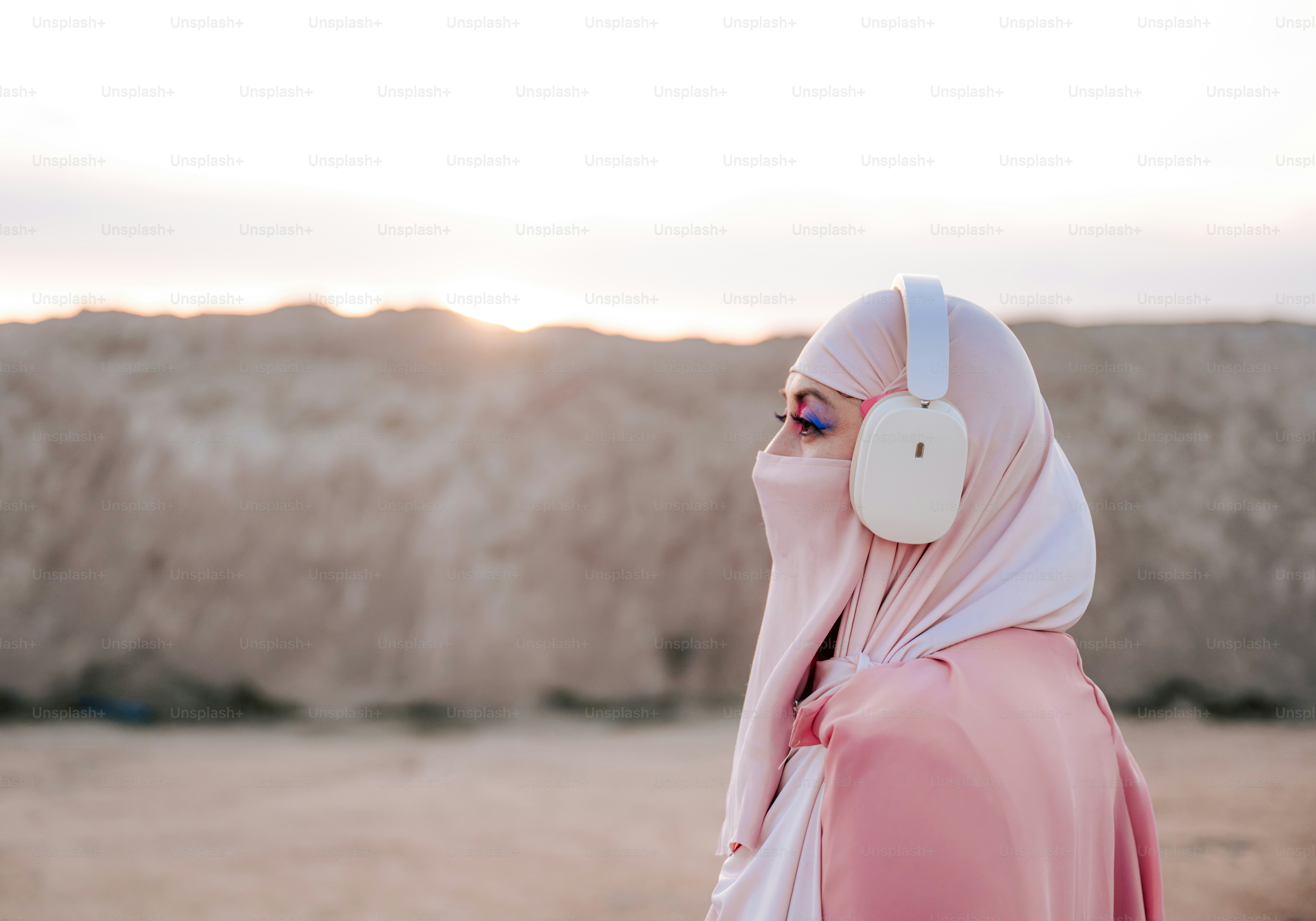 Woman wearing hijab and headphones in desert