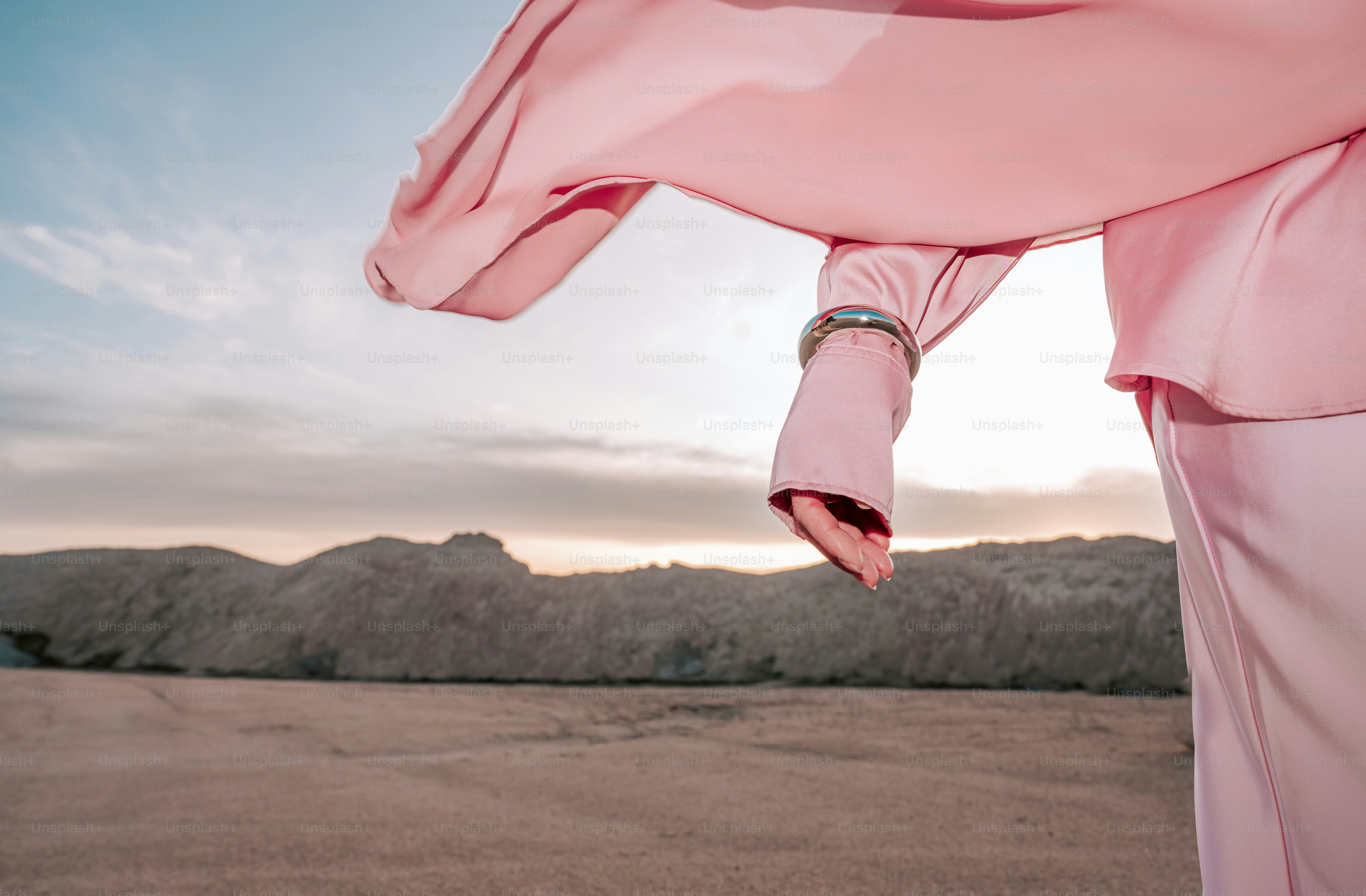Woman in pink dress with flowing fabric at sunset