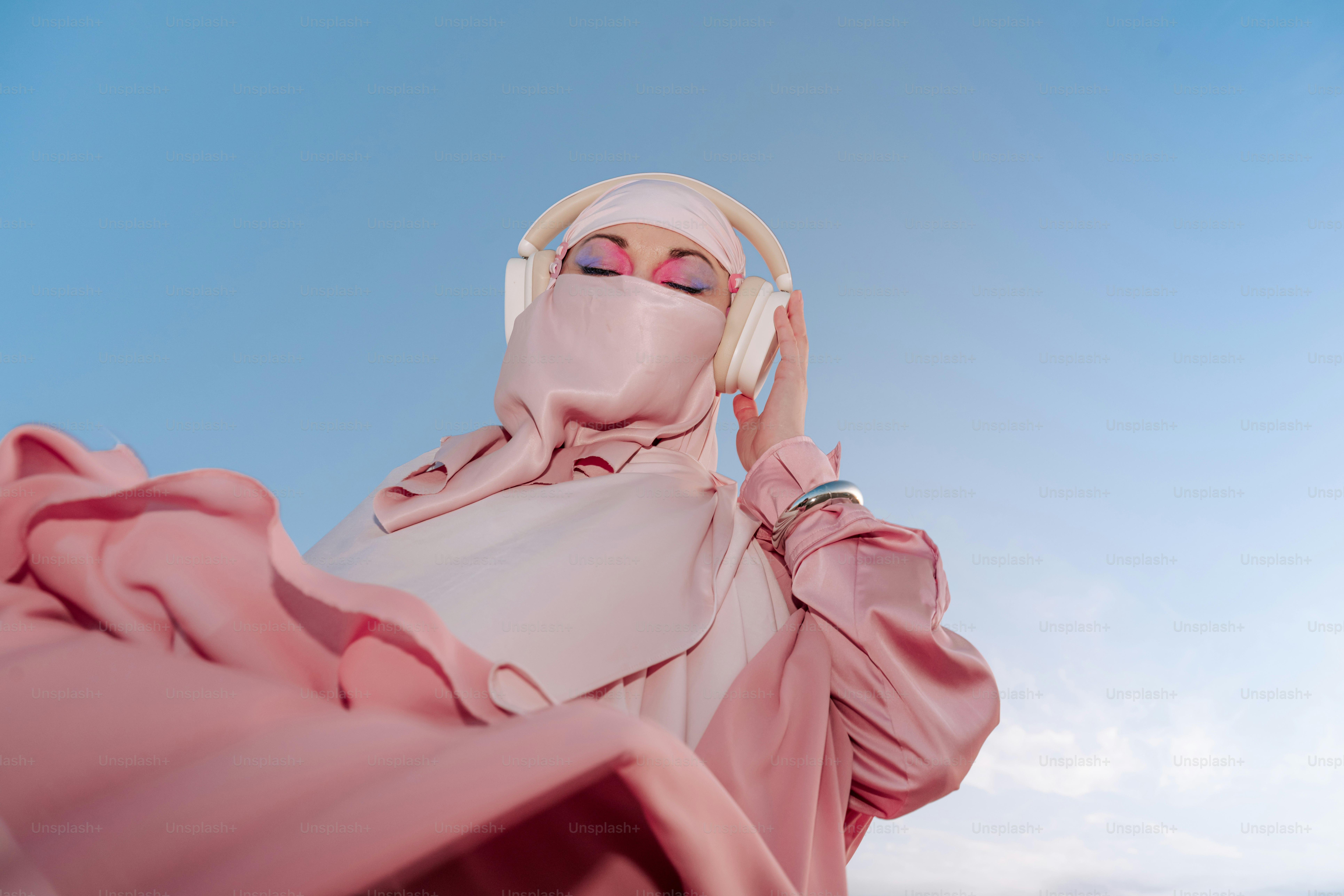 Woman in pink hijab and niqab listening to music