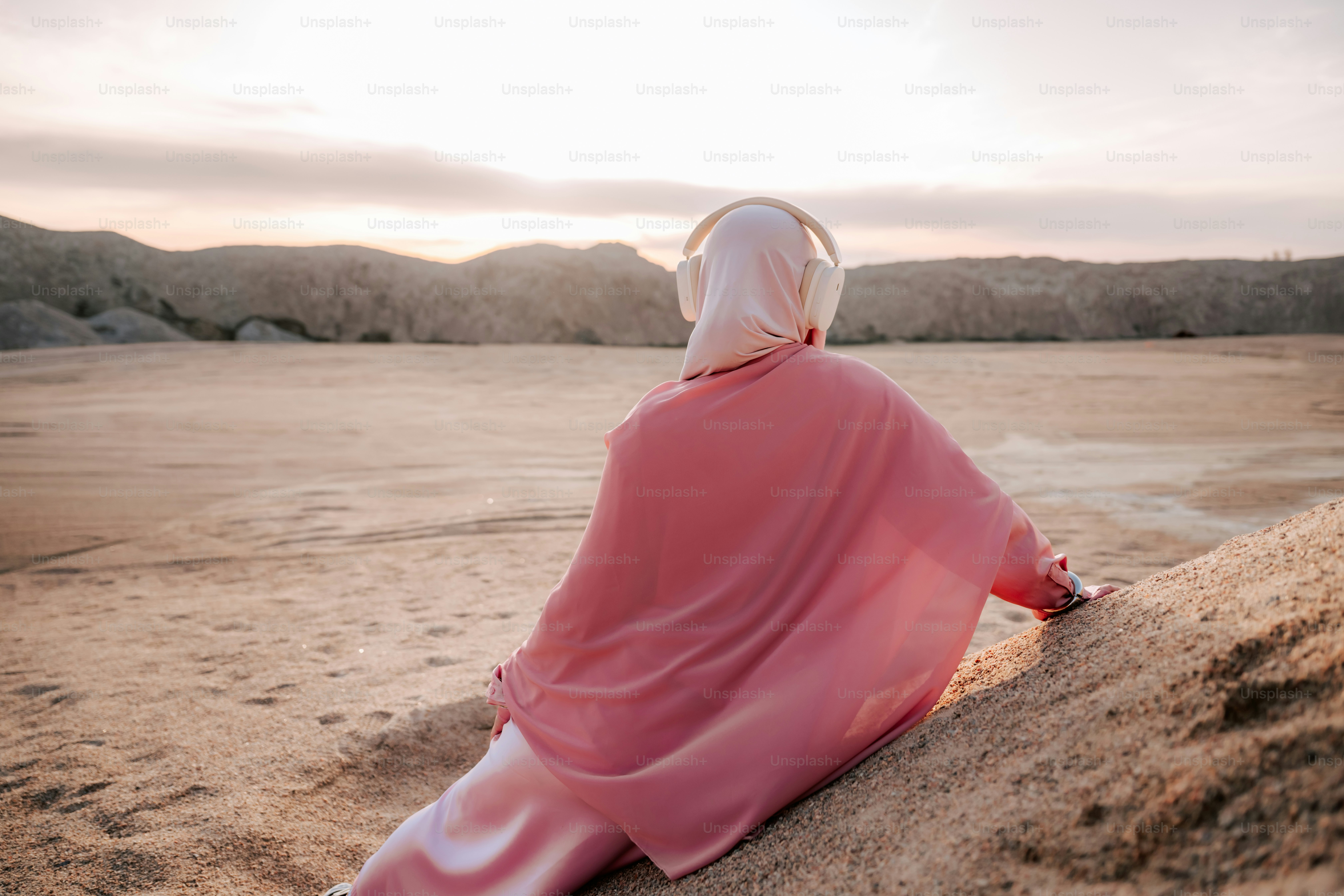 Woman in hijab and headphones enjoys desert landscape
