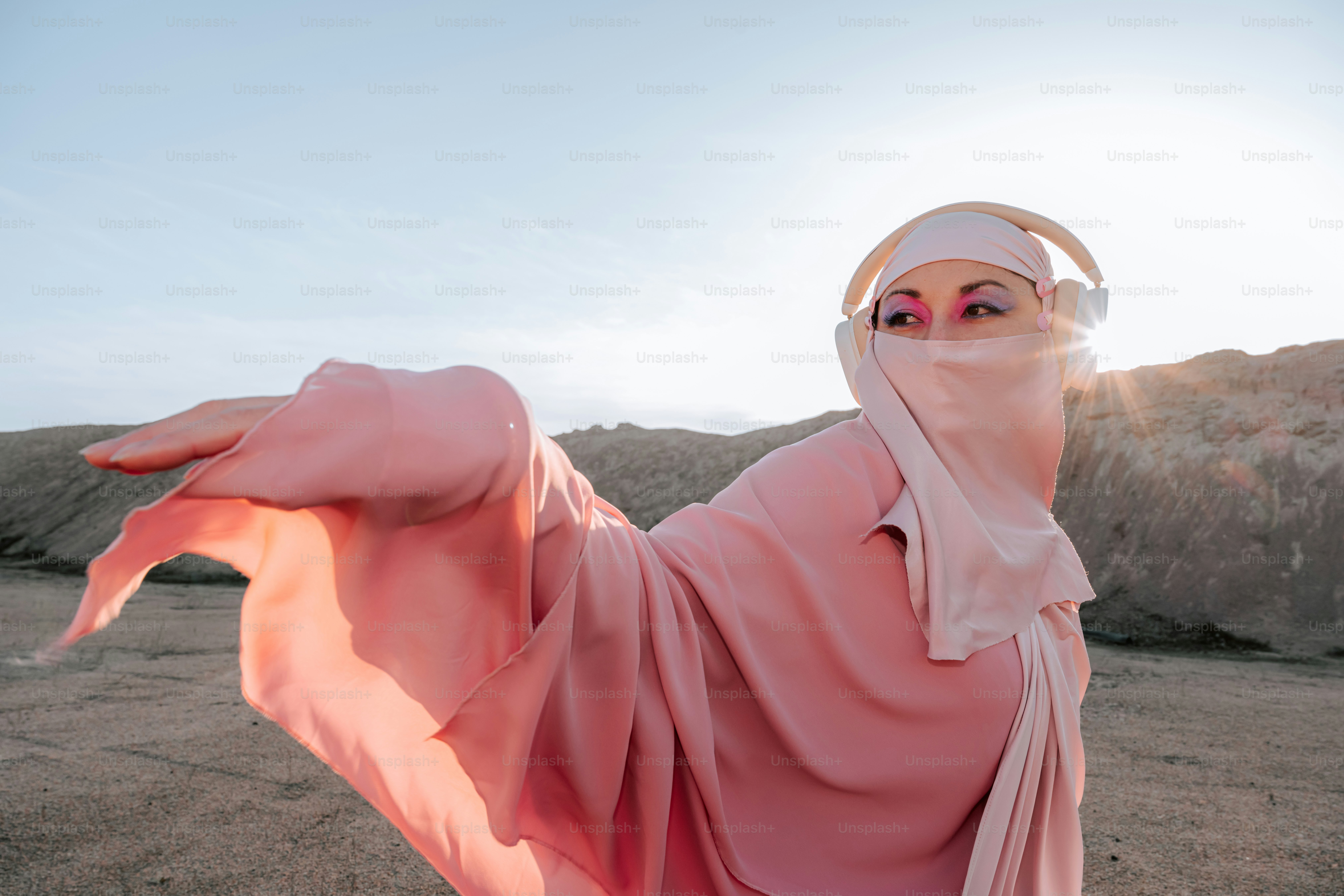 Woman in pink hijab and headphones dancing outdoors
