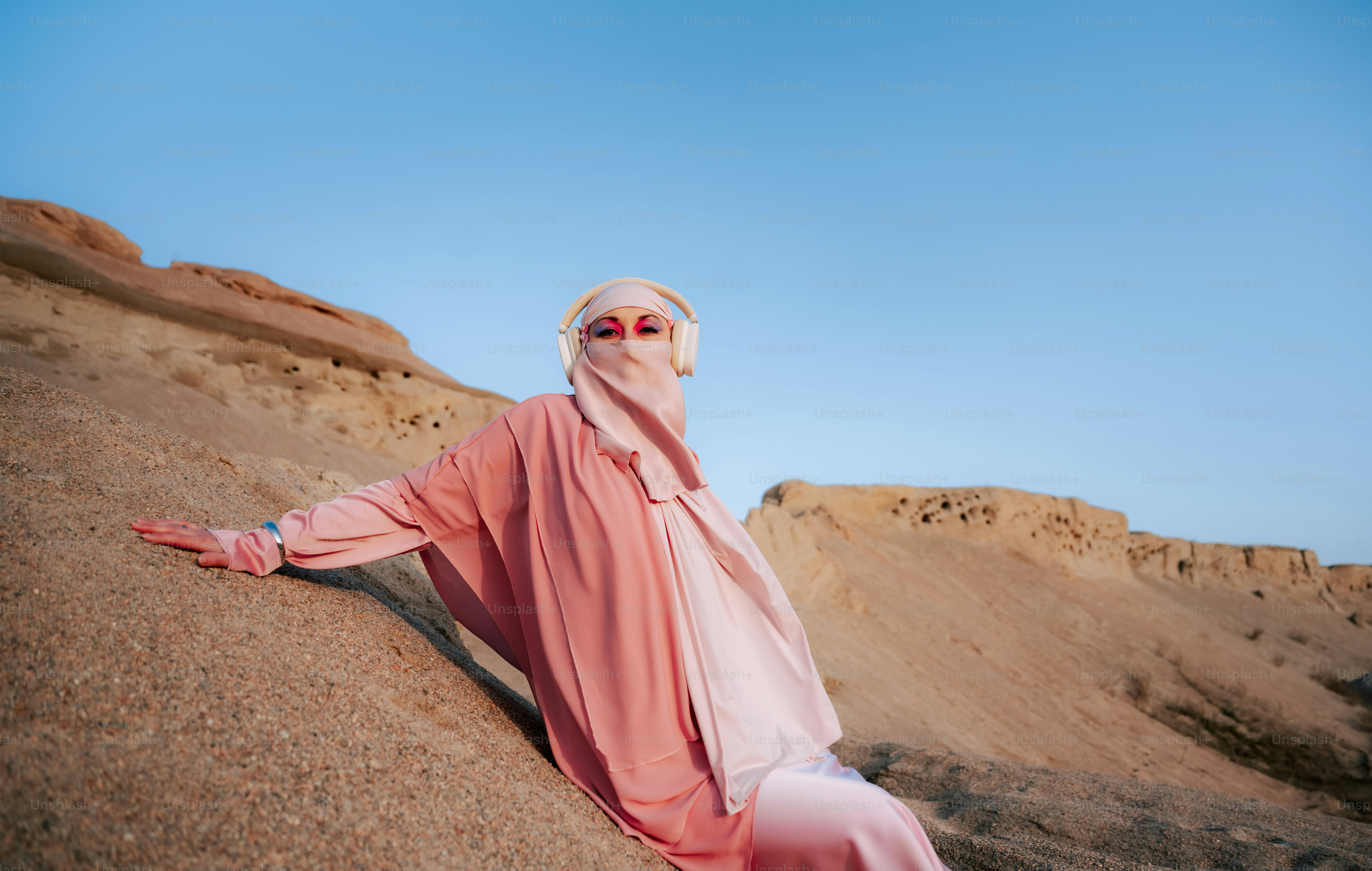 Woman in pink hijab and headphones in desert