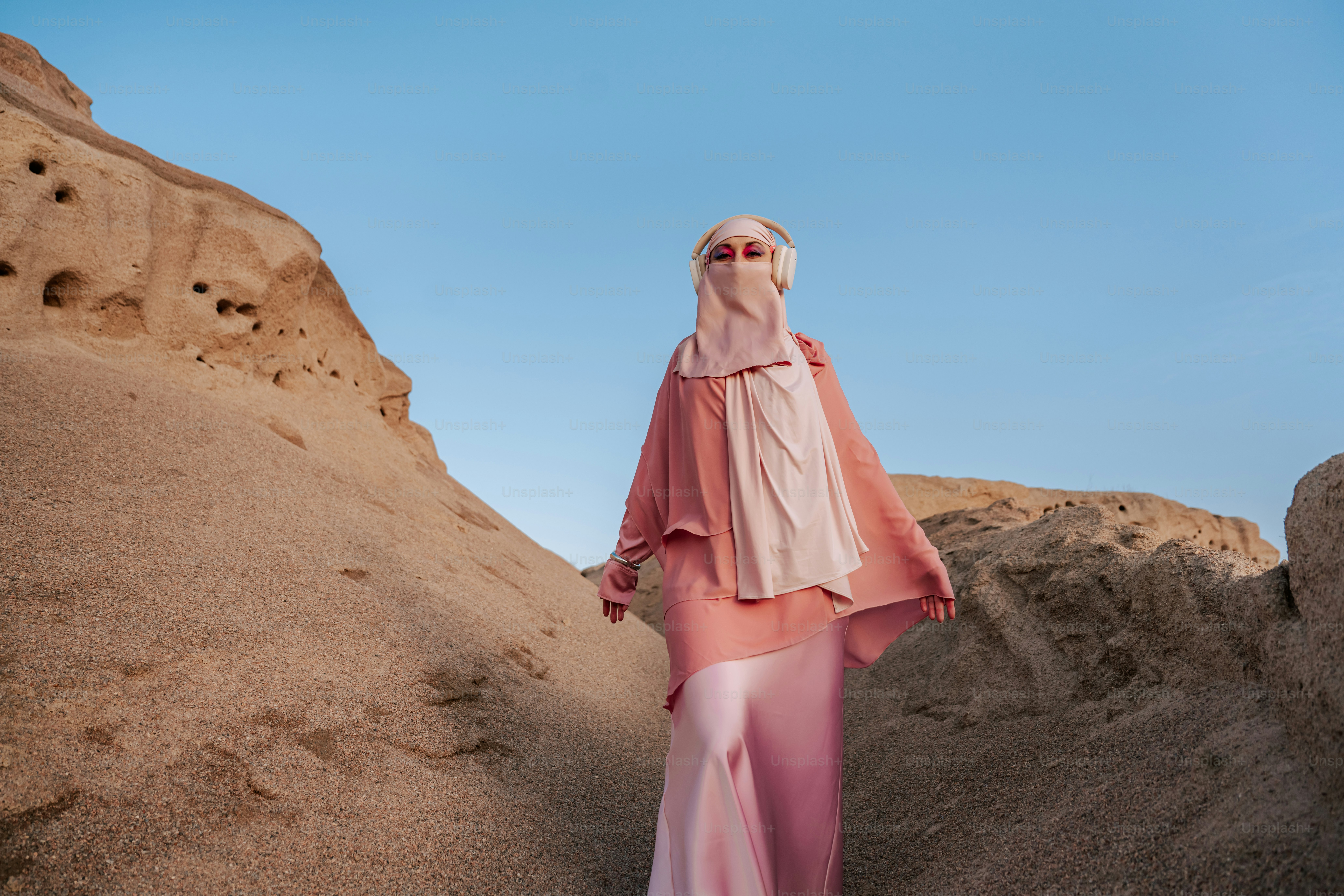 Woman in pink hijab and dress in desert landscape