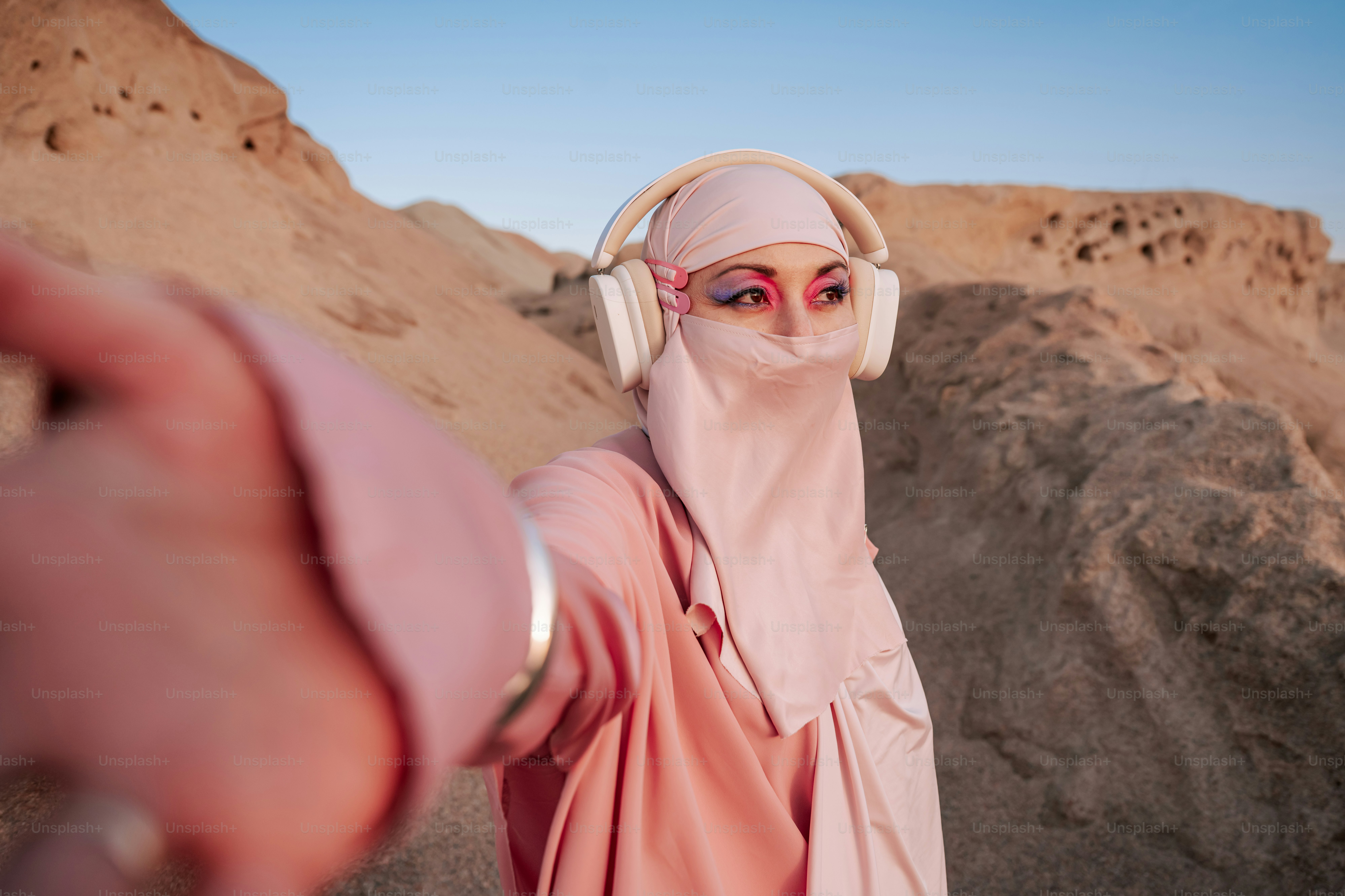 Woman in hijab and headphones in desert landscape
