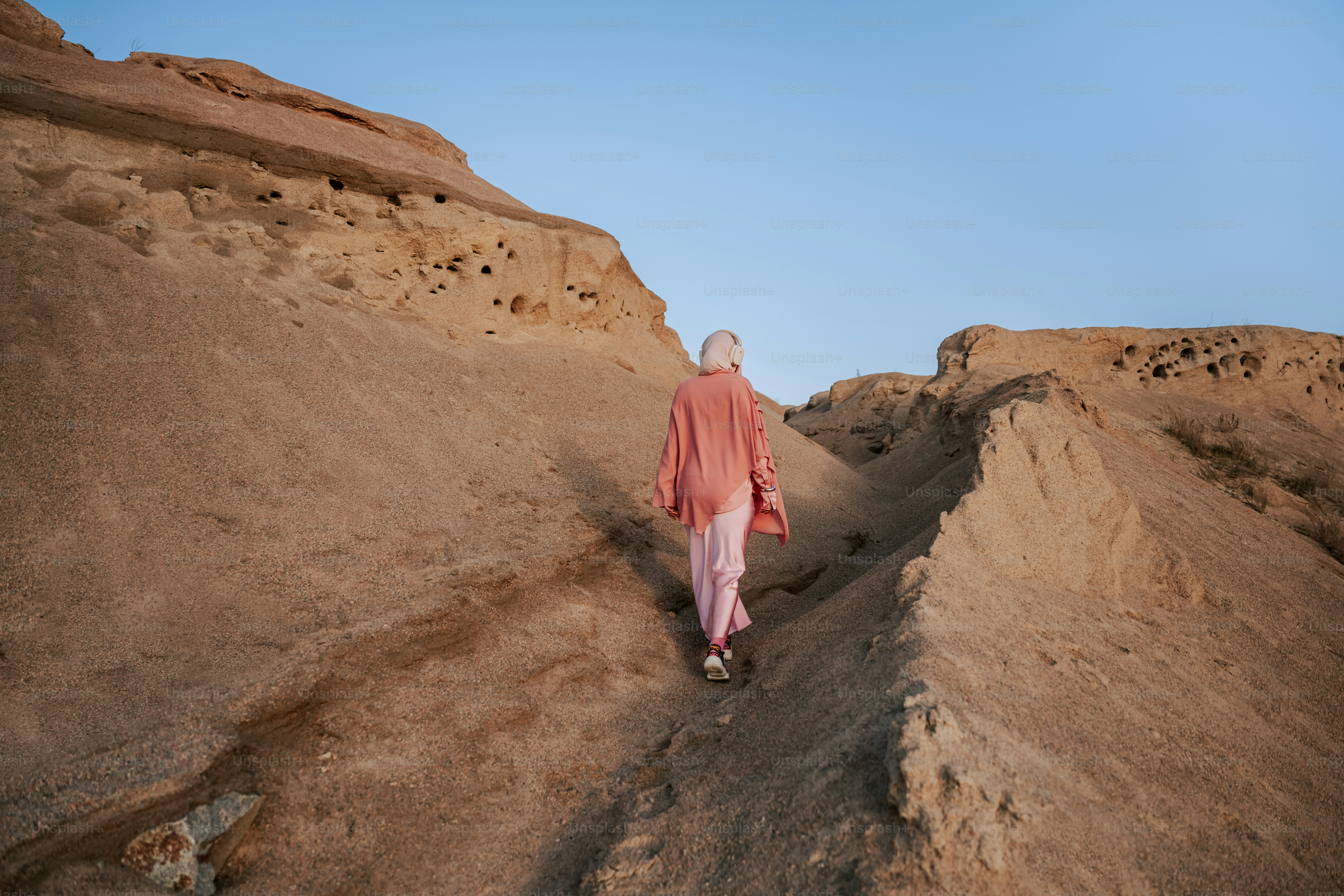 A person walks up a sandy desert hill