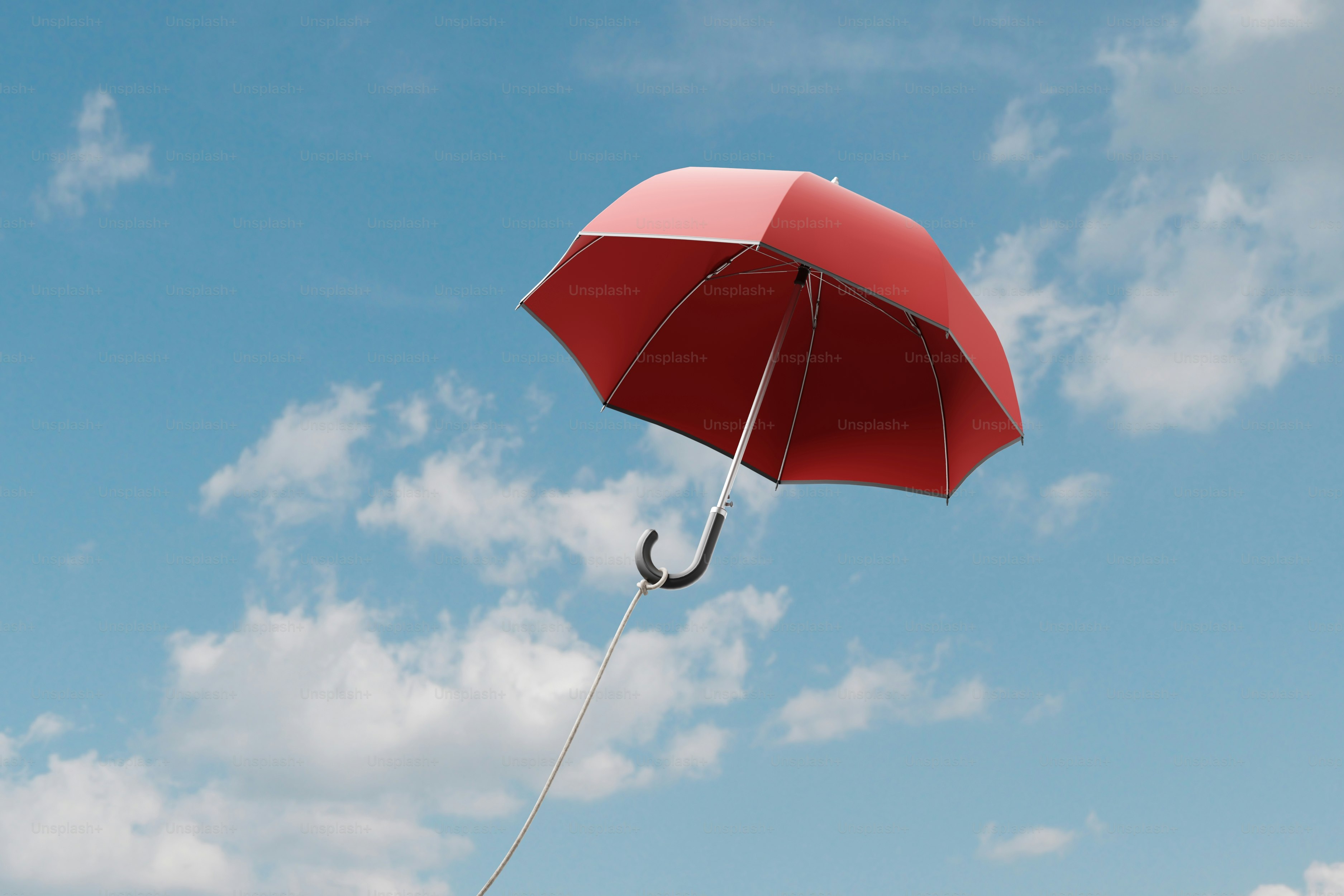 Sebuah payung merah melayang di langit biru mendung.
