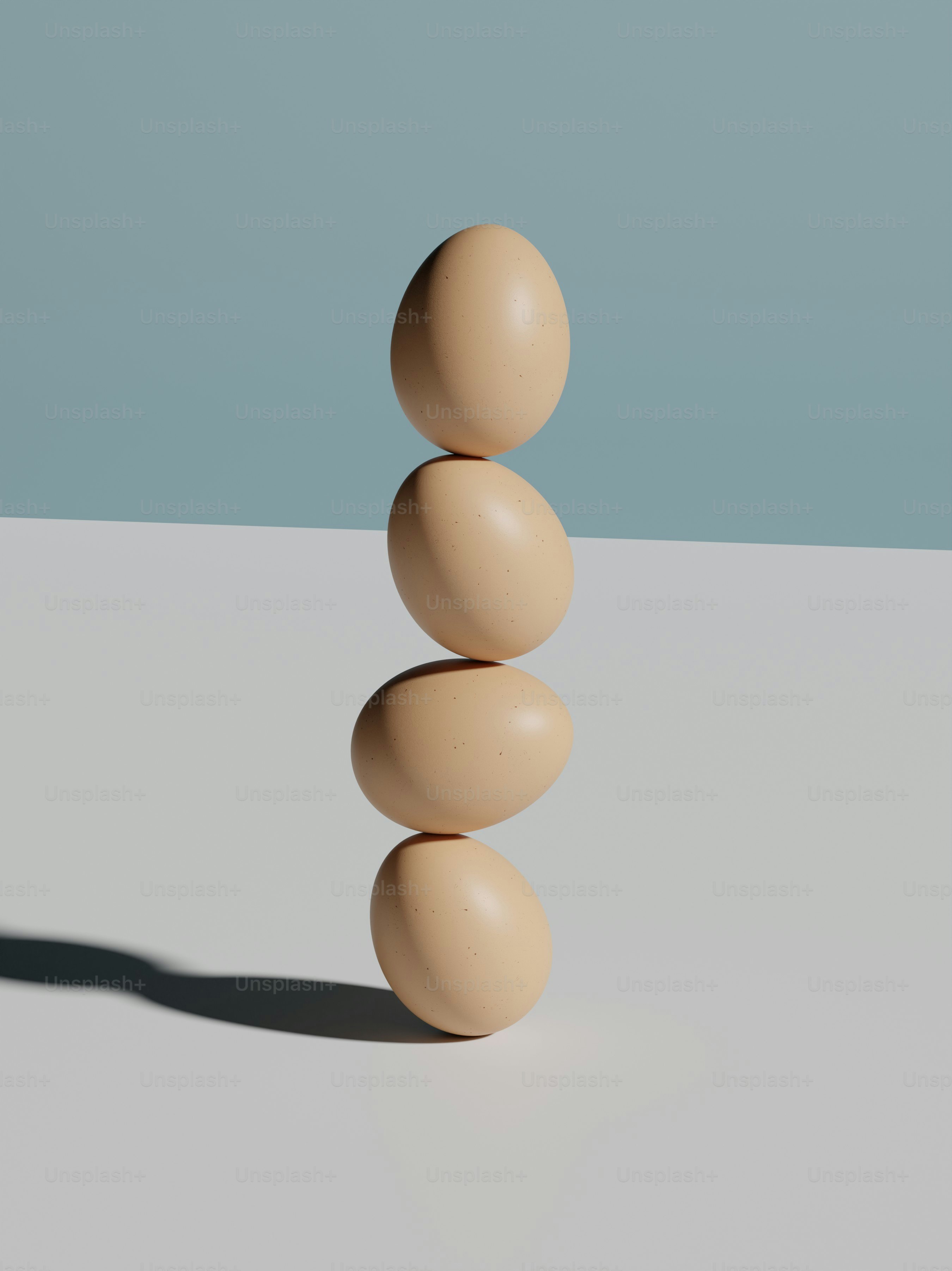 Quatre œufs empilés verticalement sur une surface blanche.