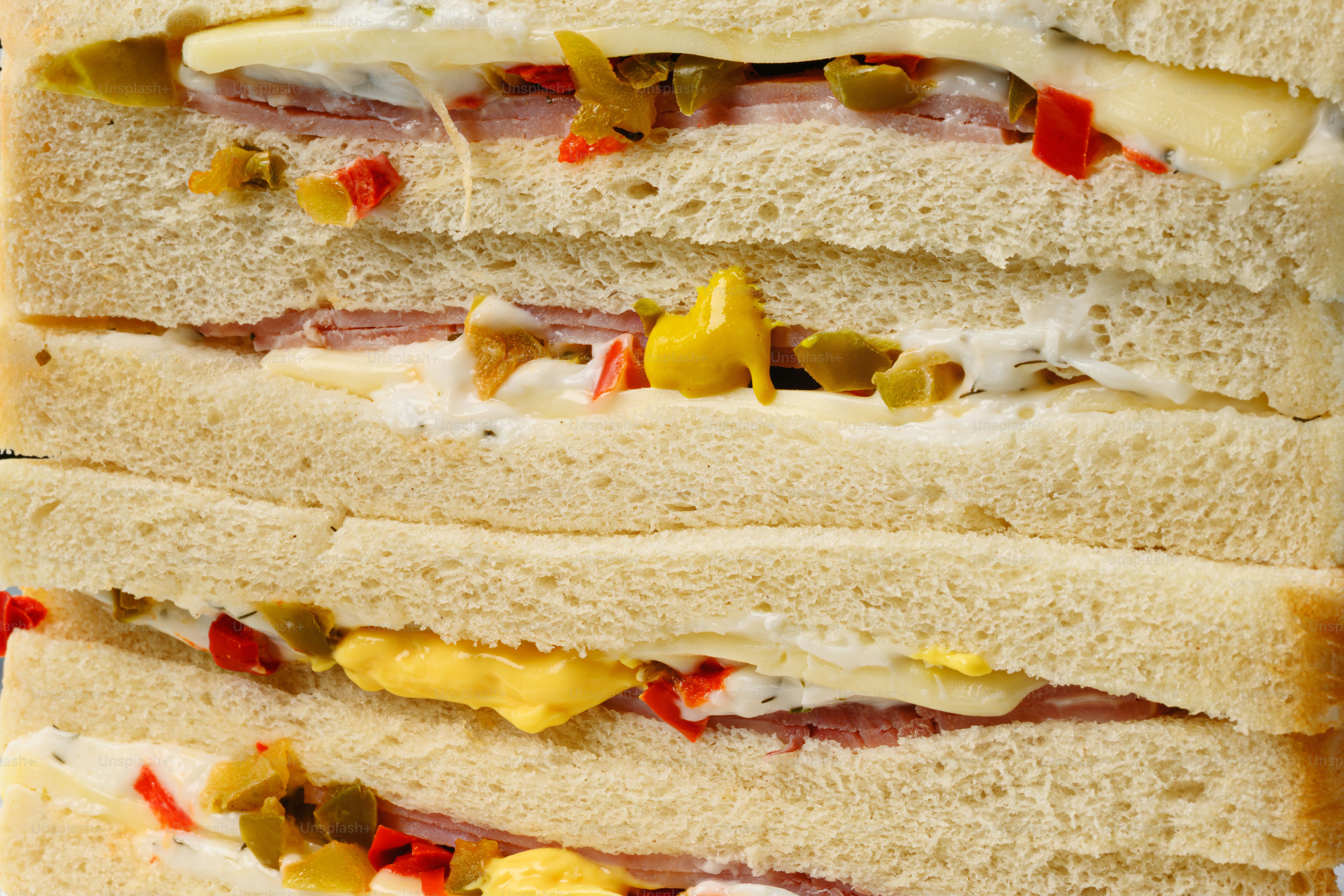 Ein gestapeltes Sandwich mit Schinken, Käse und Gemüse.