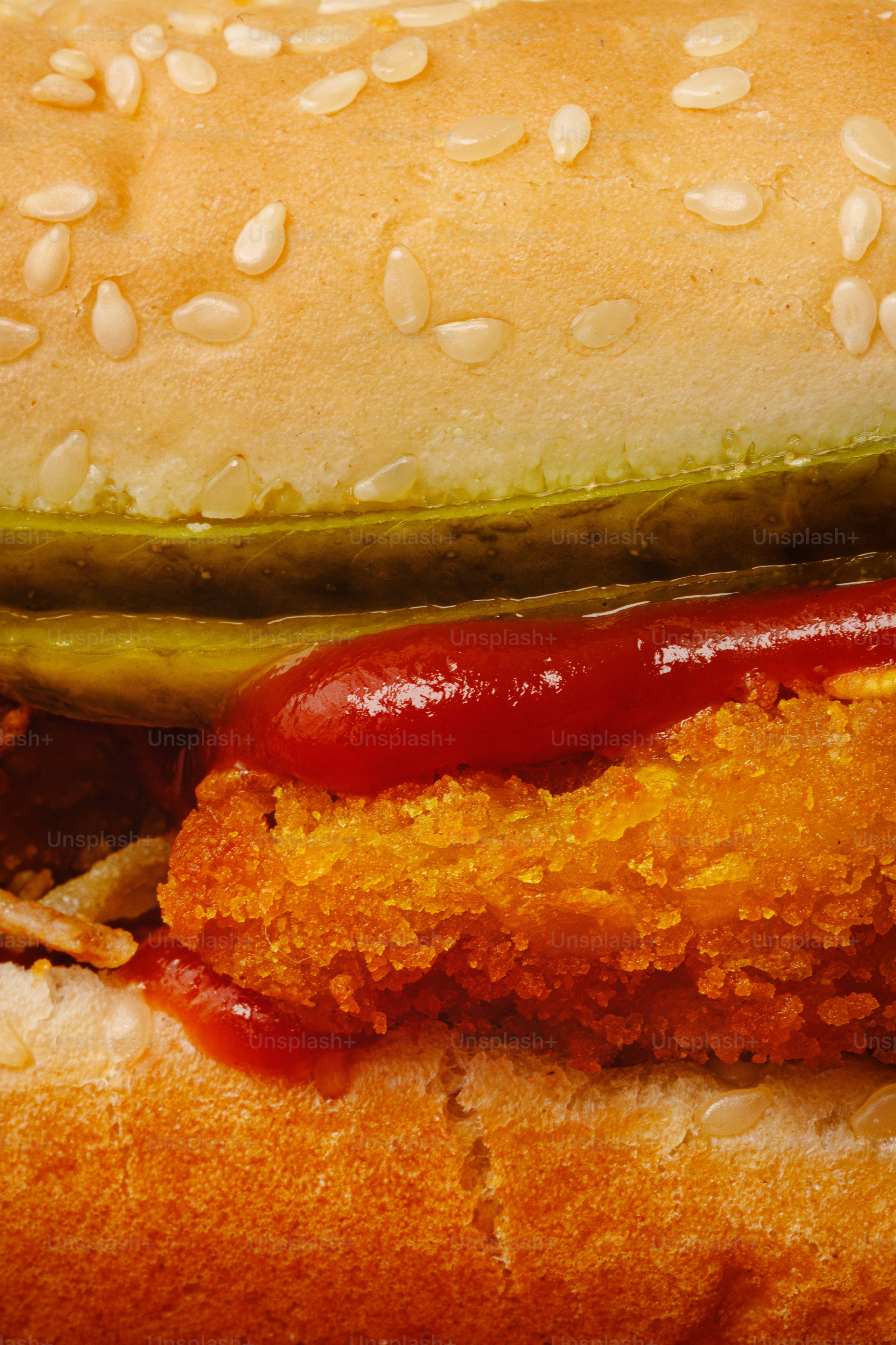 Nahaufnahme eines knusprigen Hähnchensandwiches mit Ketchup und Gurken.