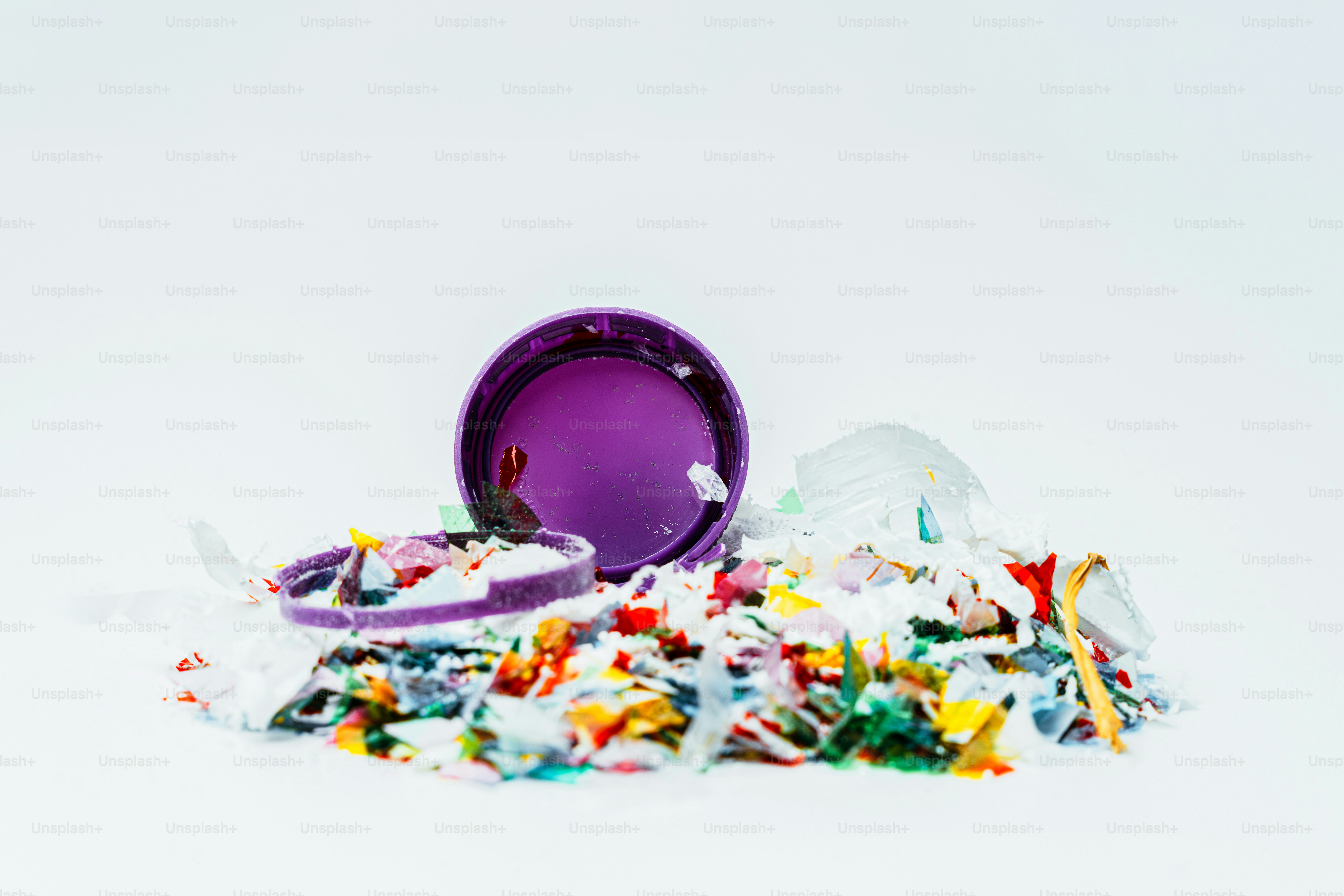 Pile of colorful confetti spilling from a purple container