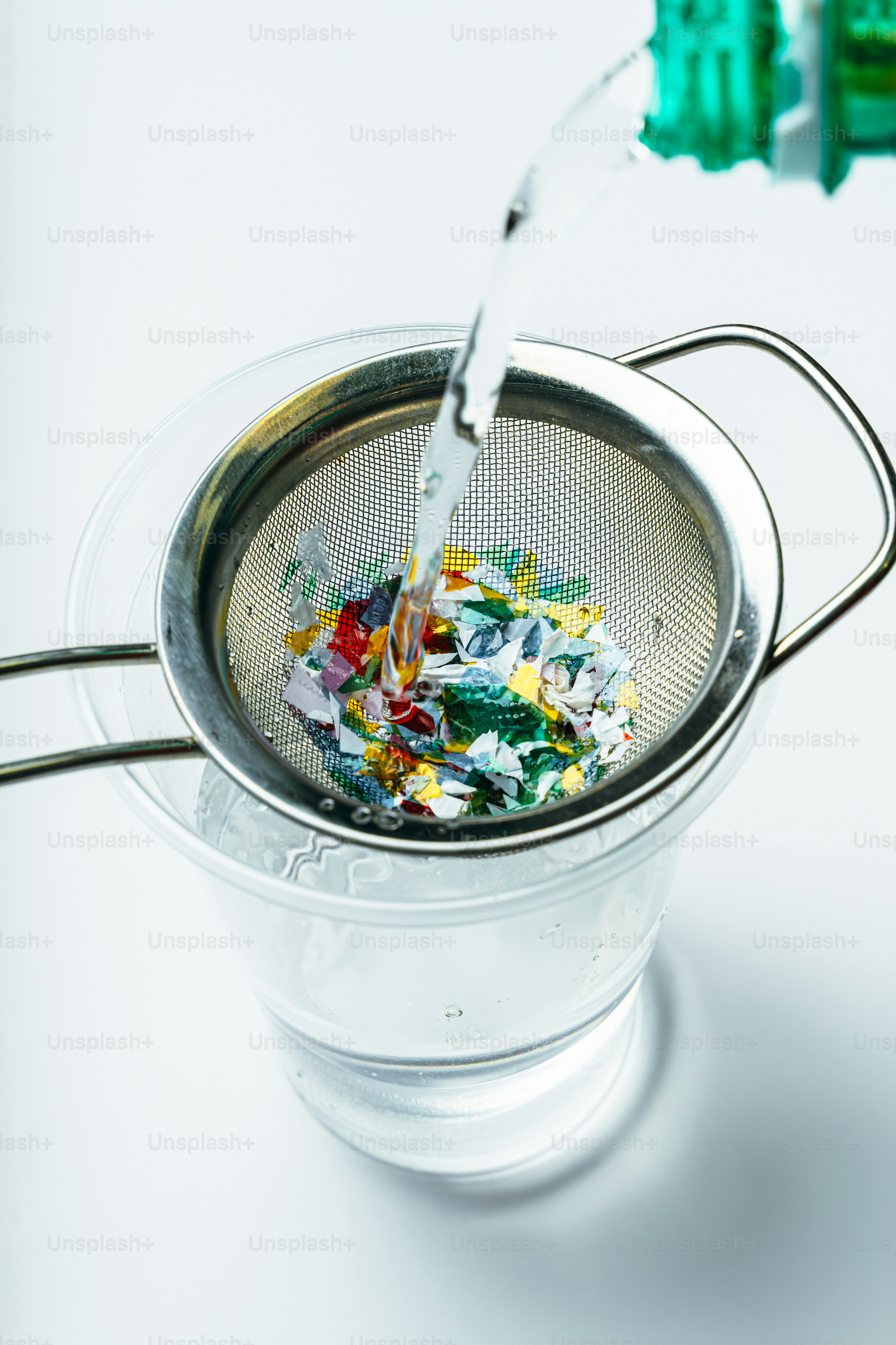 Acqua che scorre attraverso un setaccio con coriandoli colorati.