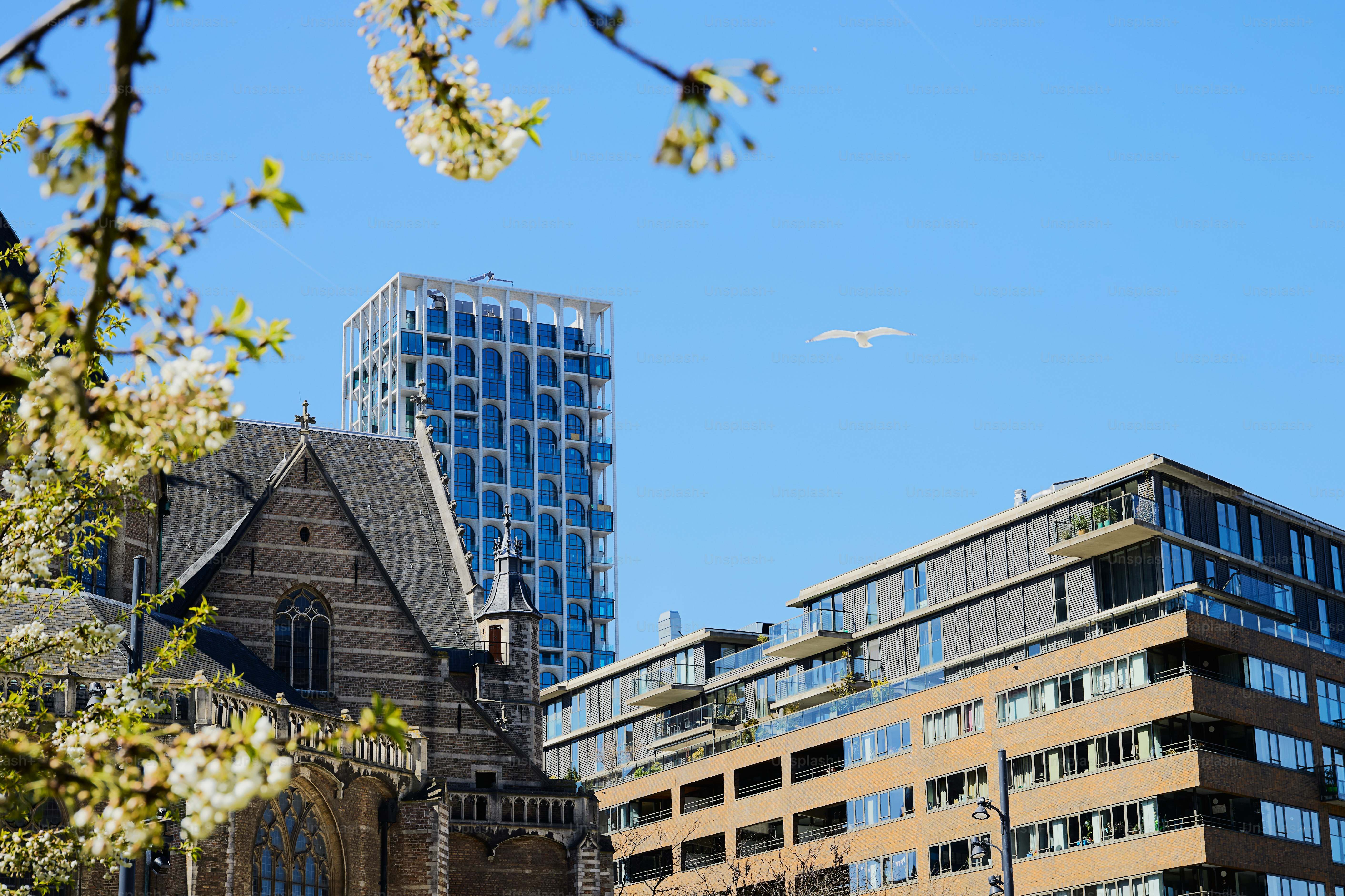 Moderne Gebäude und eine alte Kirche unter klarem blauen Himmel.