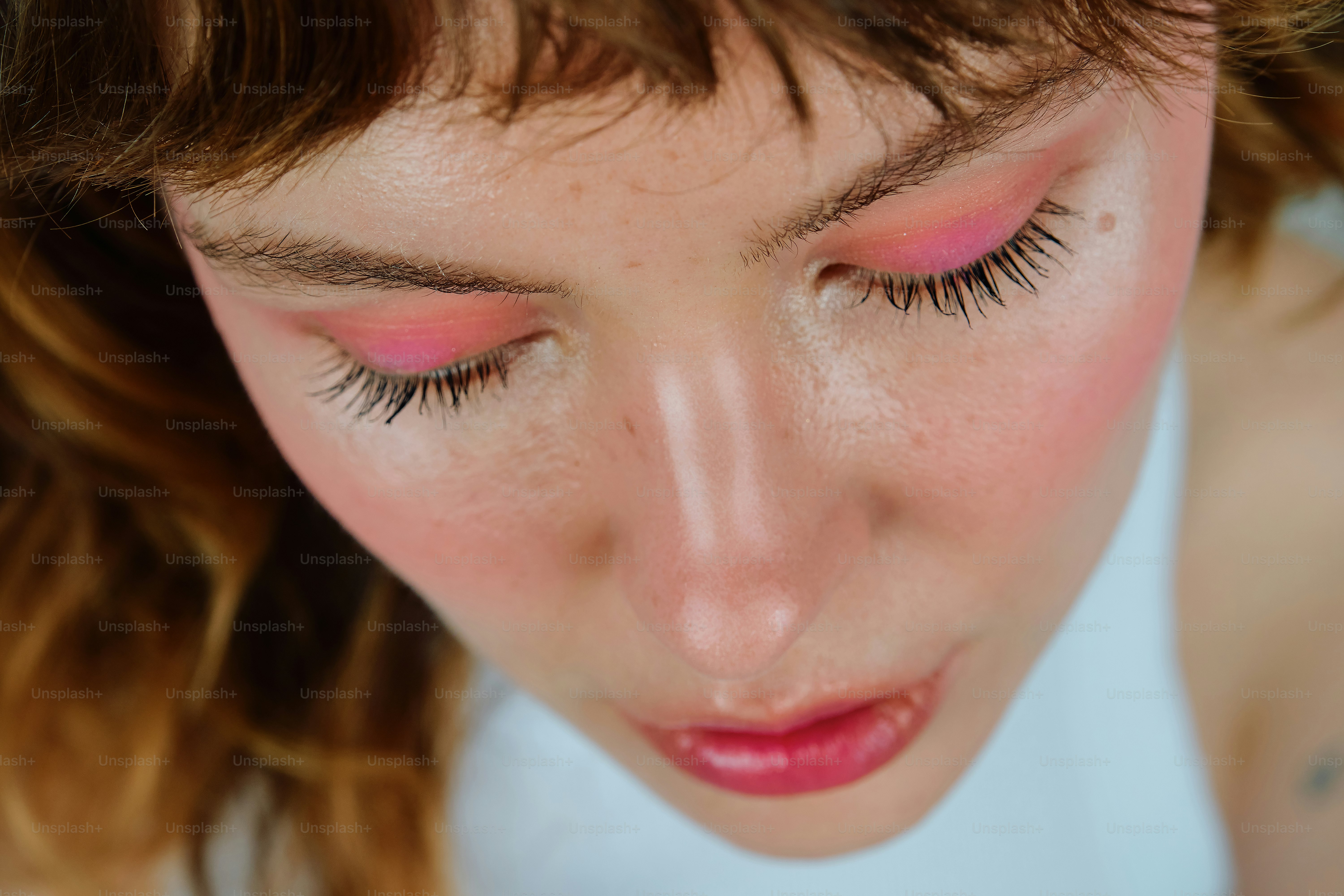 Wanita muda dengan eyeshadow merah muda cerah dan perona pipi.