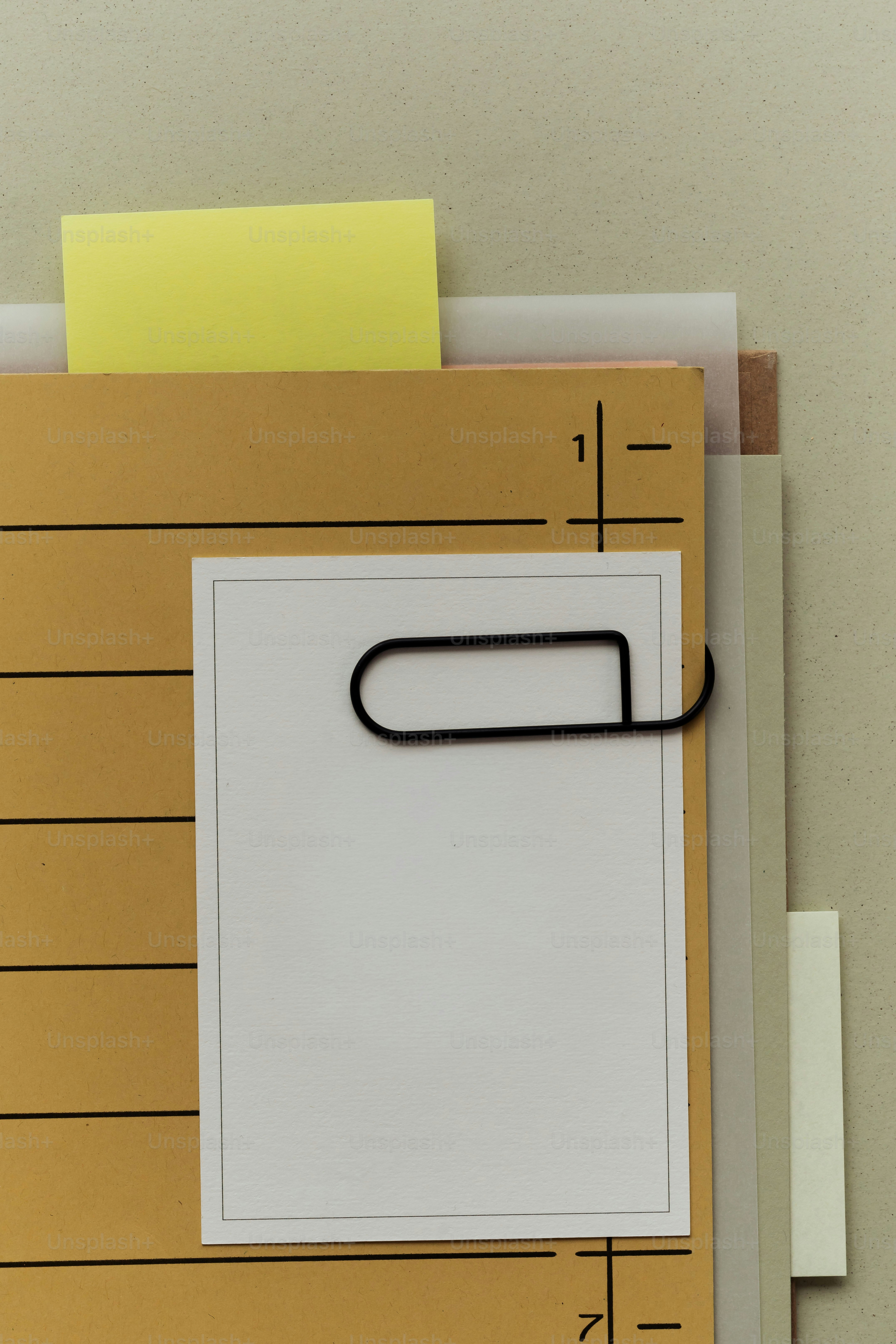 A paperclip holds a small white card on a folder.