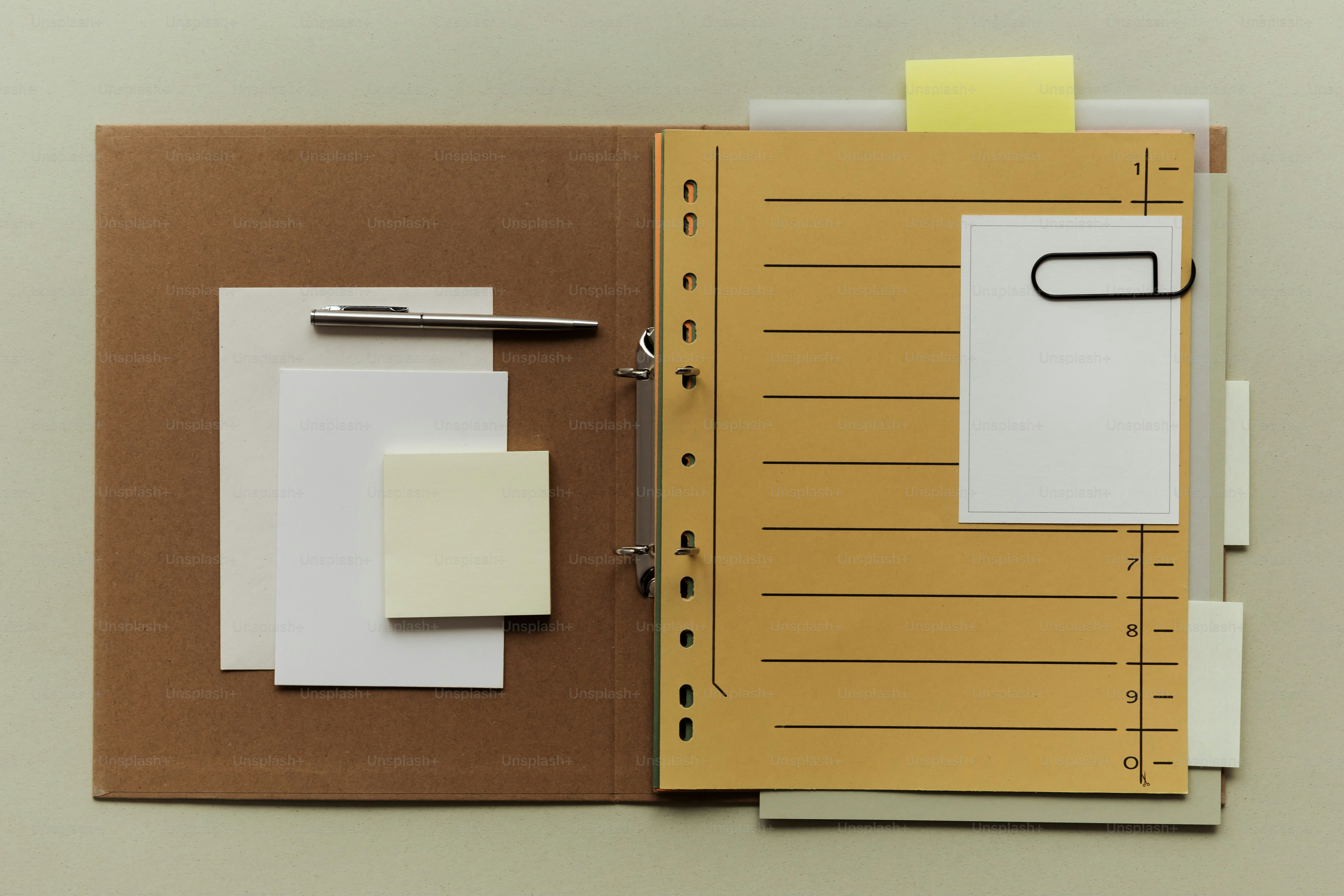 Open binder with papers, sticky notes, and a pen.