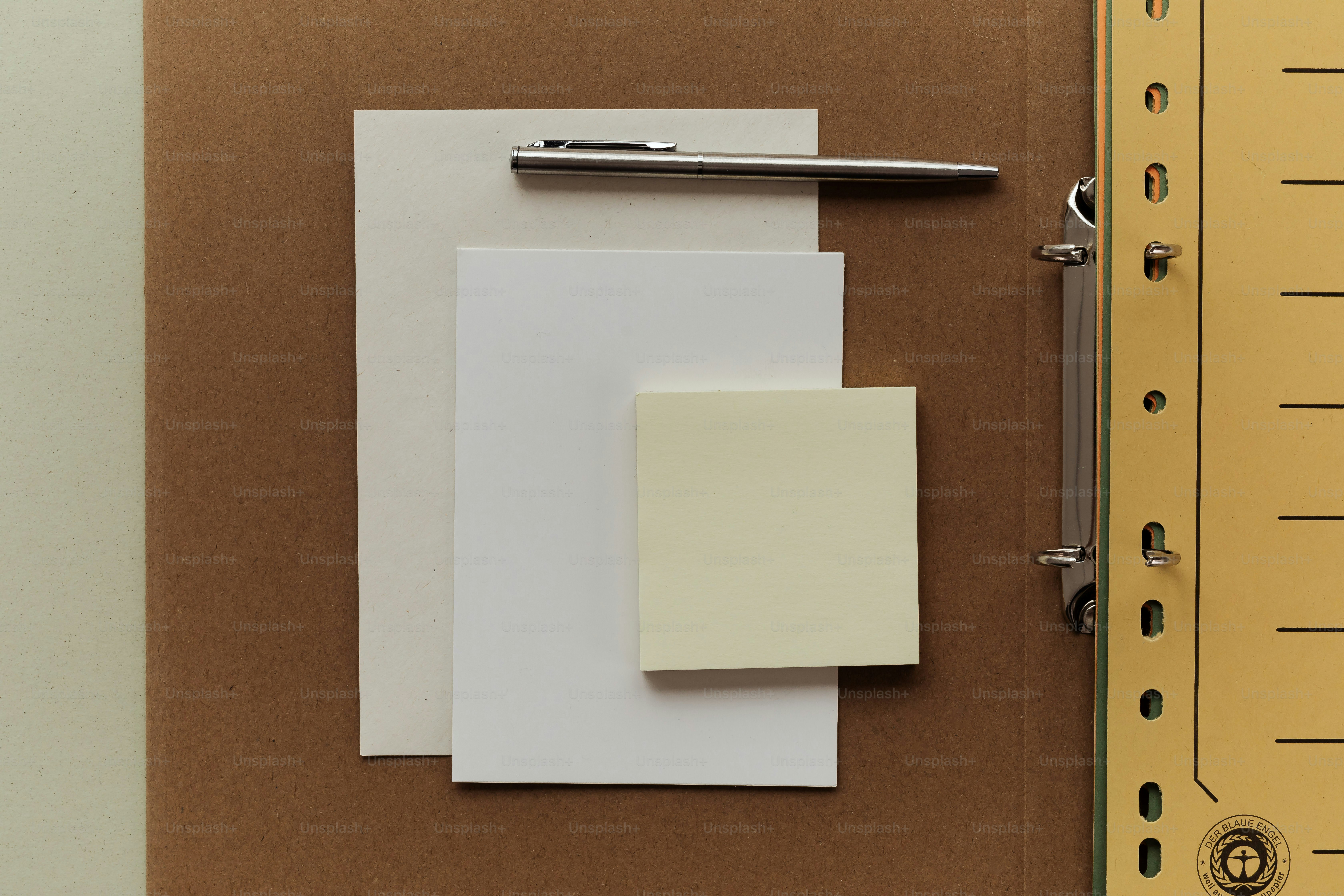 A pen rests on blank papers and sticky notes.
