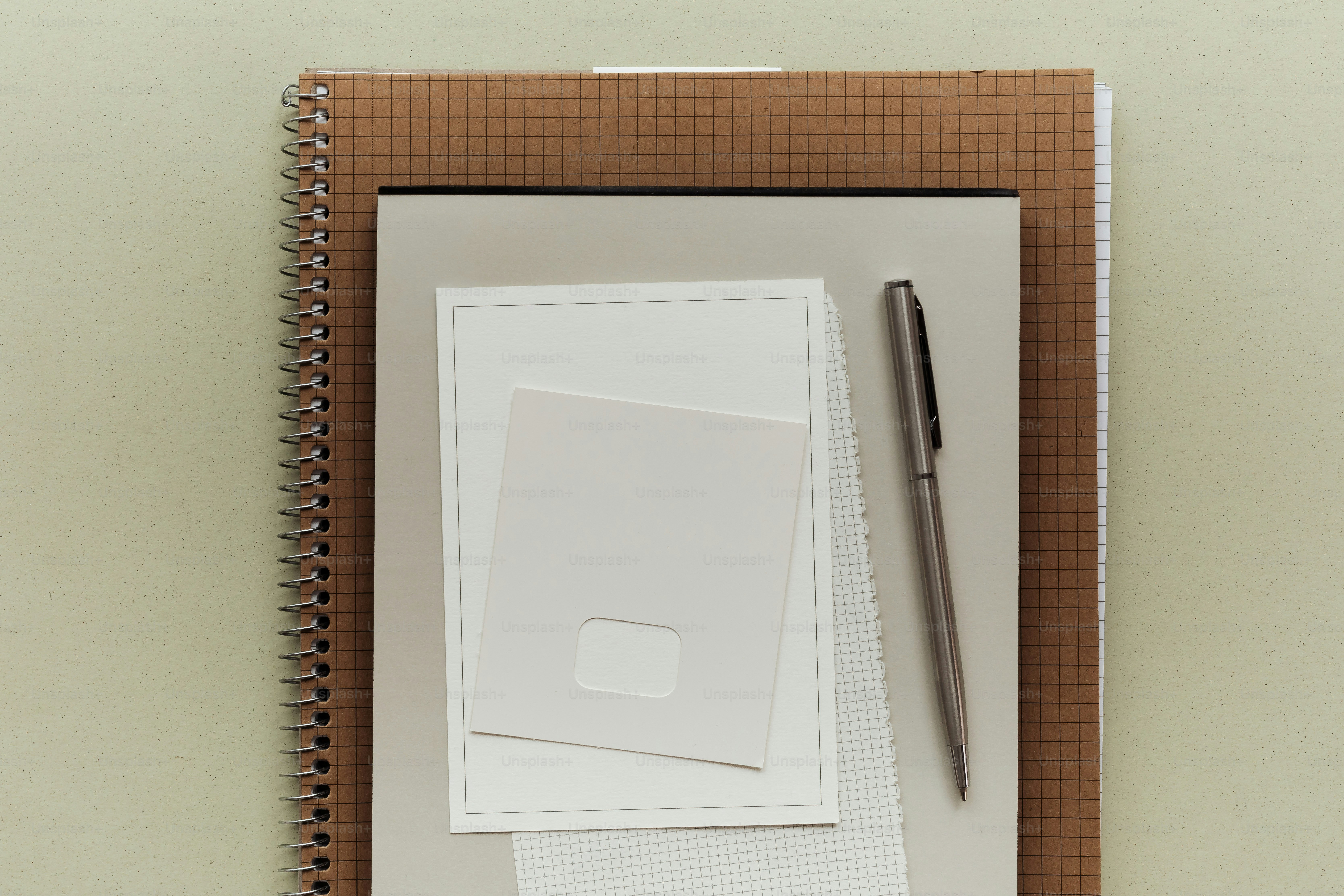 Notebooks and pen arranged neatly on a light background.