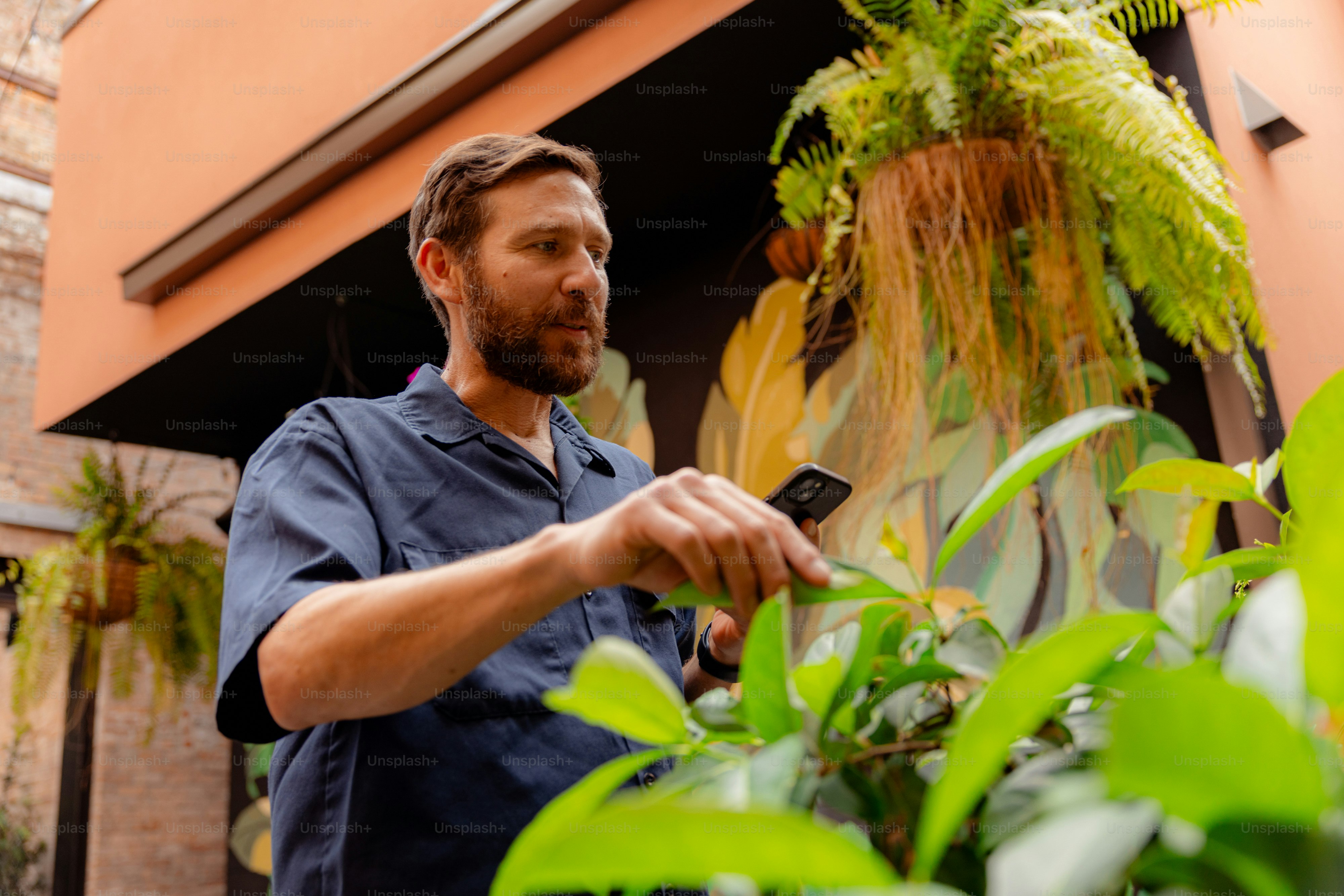 Hombre usando un smartphone cerca de plantas verdes y exuberantes