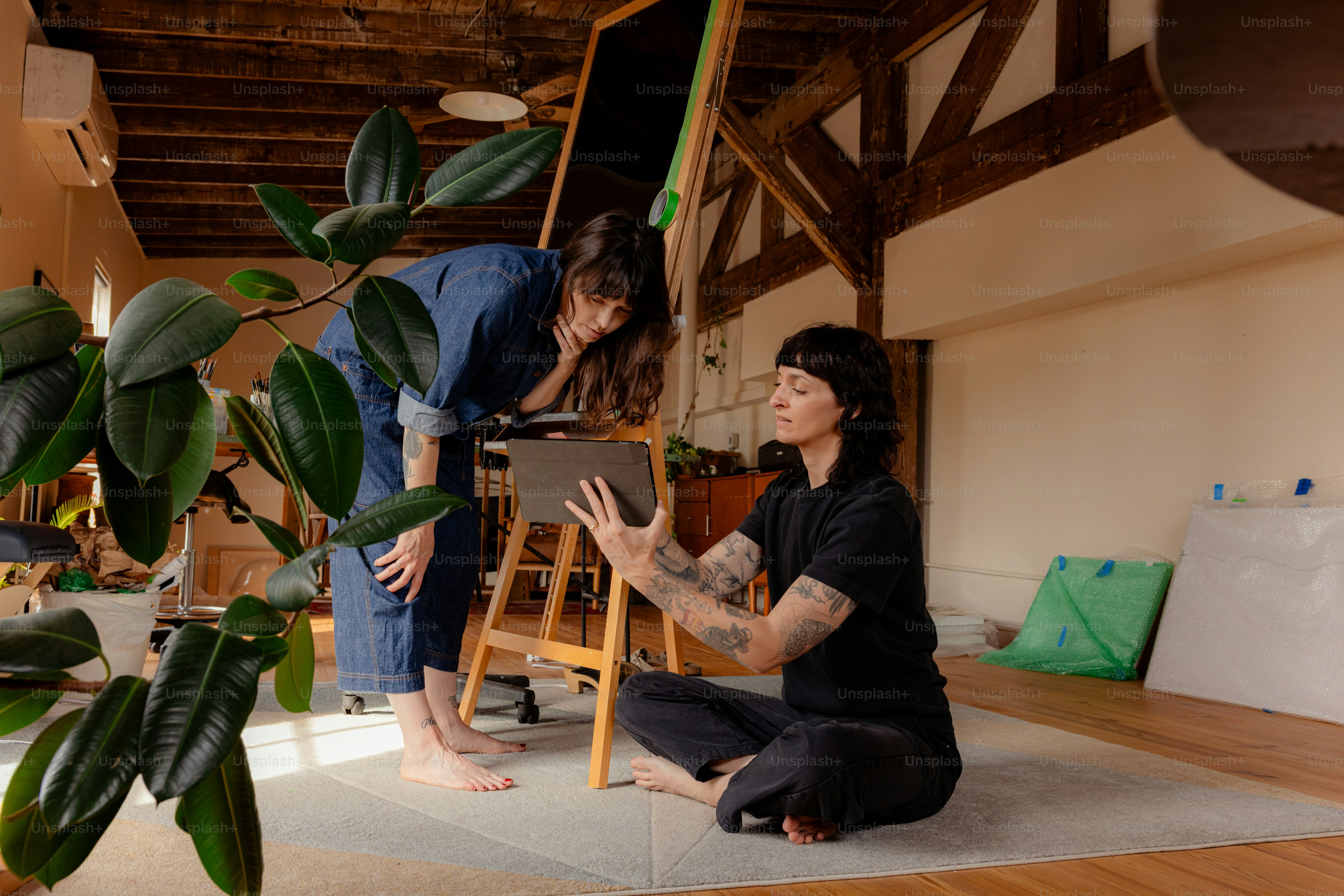 Dos mujeres mirando una tableta en un estudio luminoso.