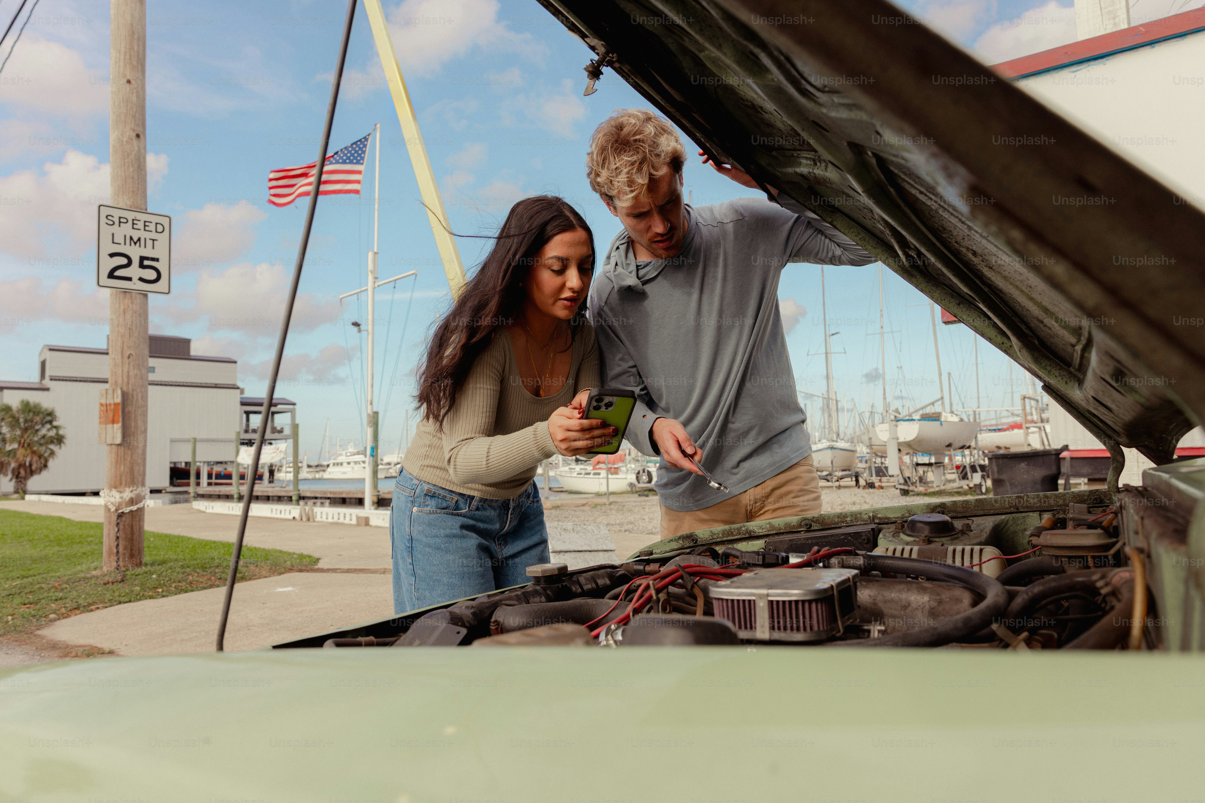 Pareja mirando un motor de coche con un smartphone