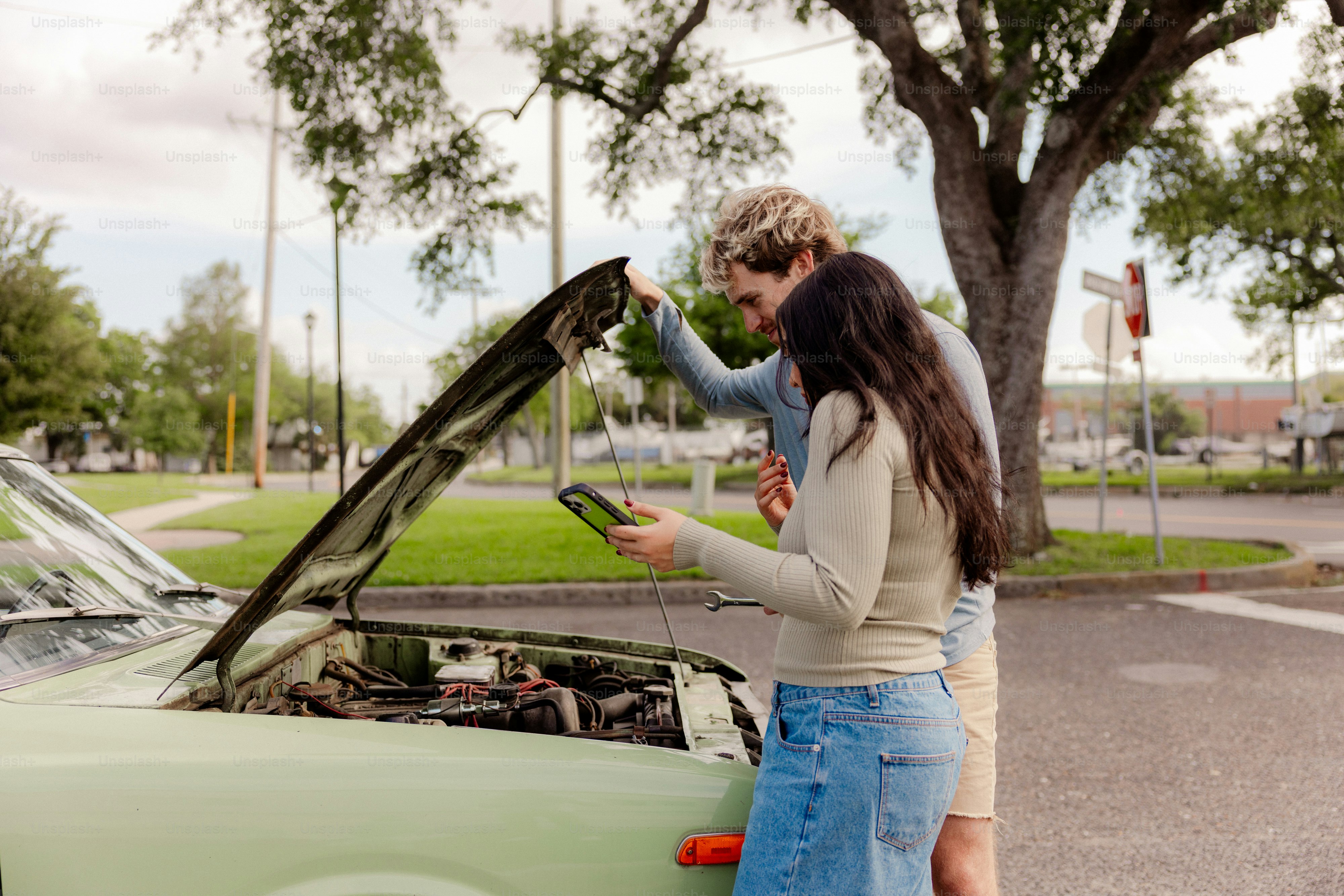 Pareja mirando el motor del coche con el móvil