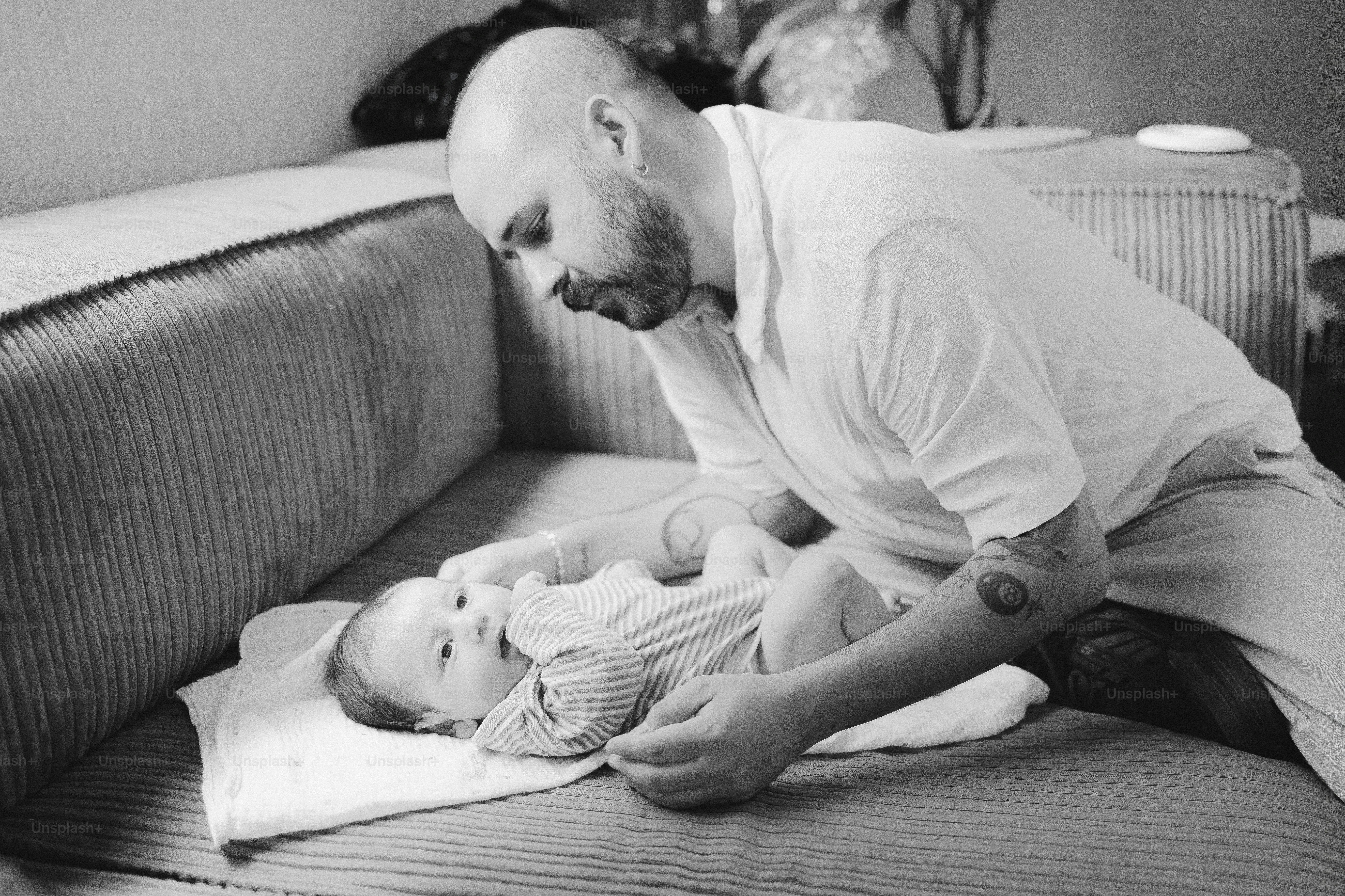 Un homme qui change la couche du bébé sur un canapé