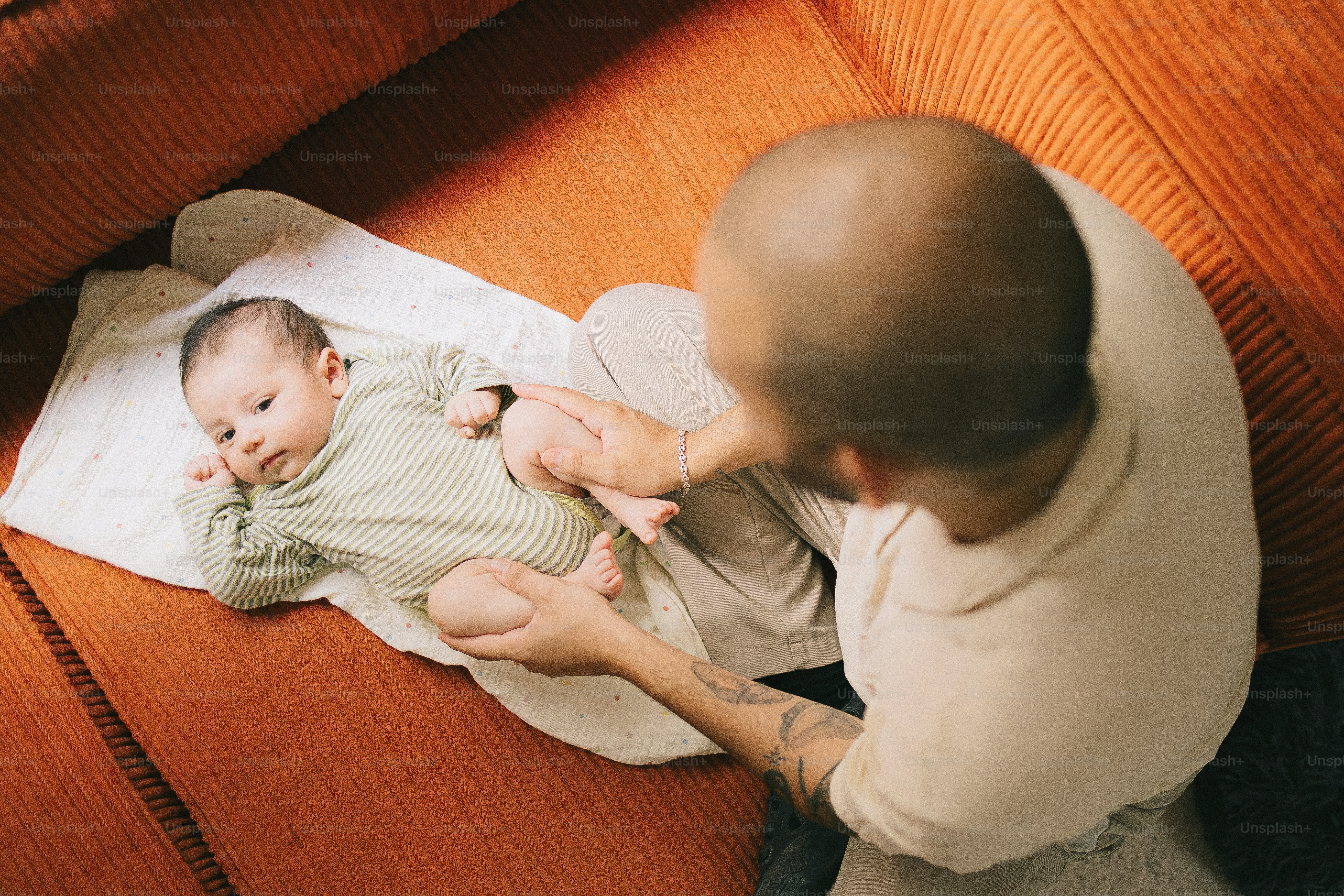 Père qui change la couche du bébé sur un canapé