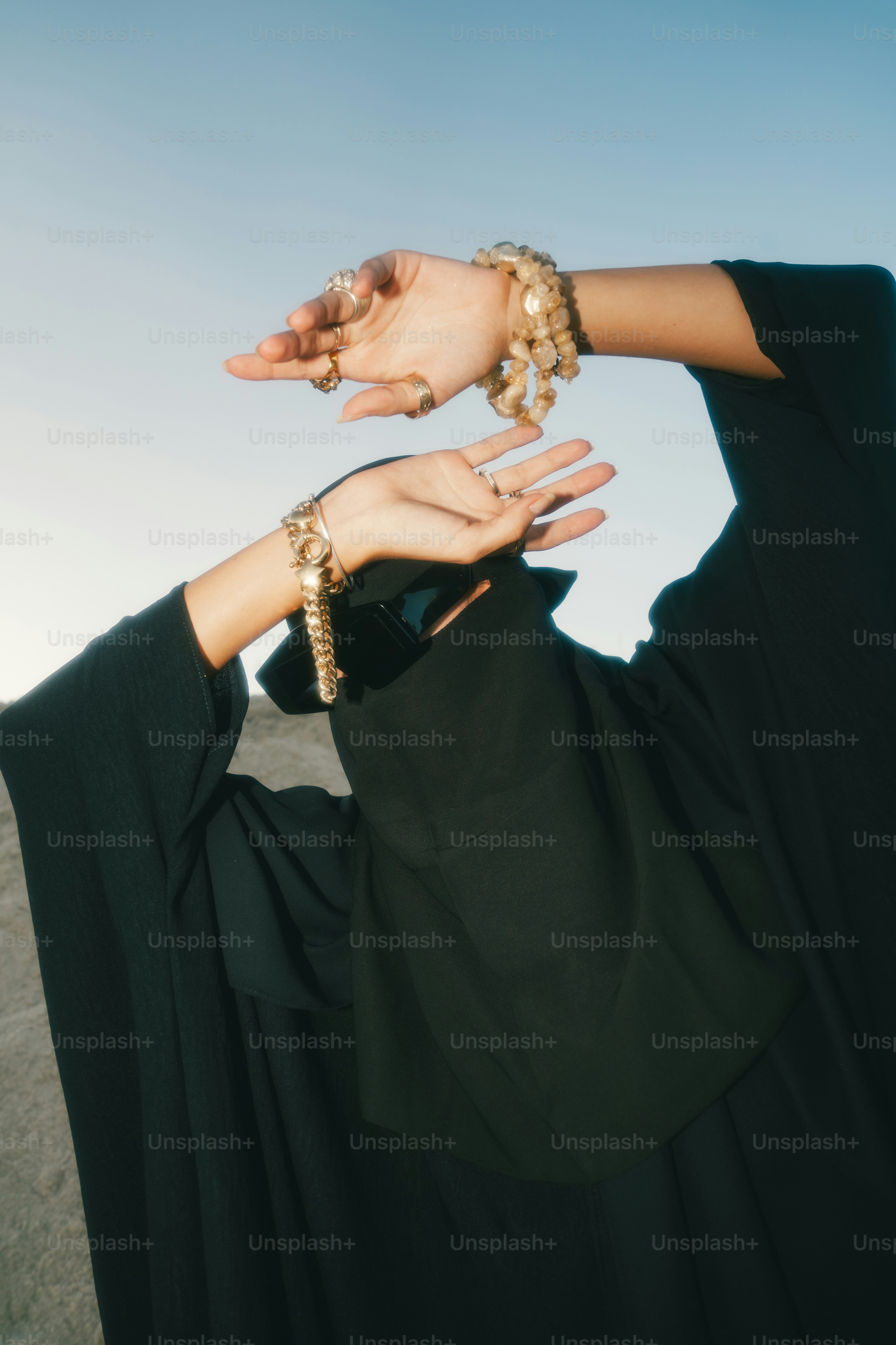 Wanita berbaju abaya hitam dengan perhiasan berpose dengan tangan