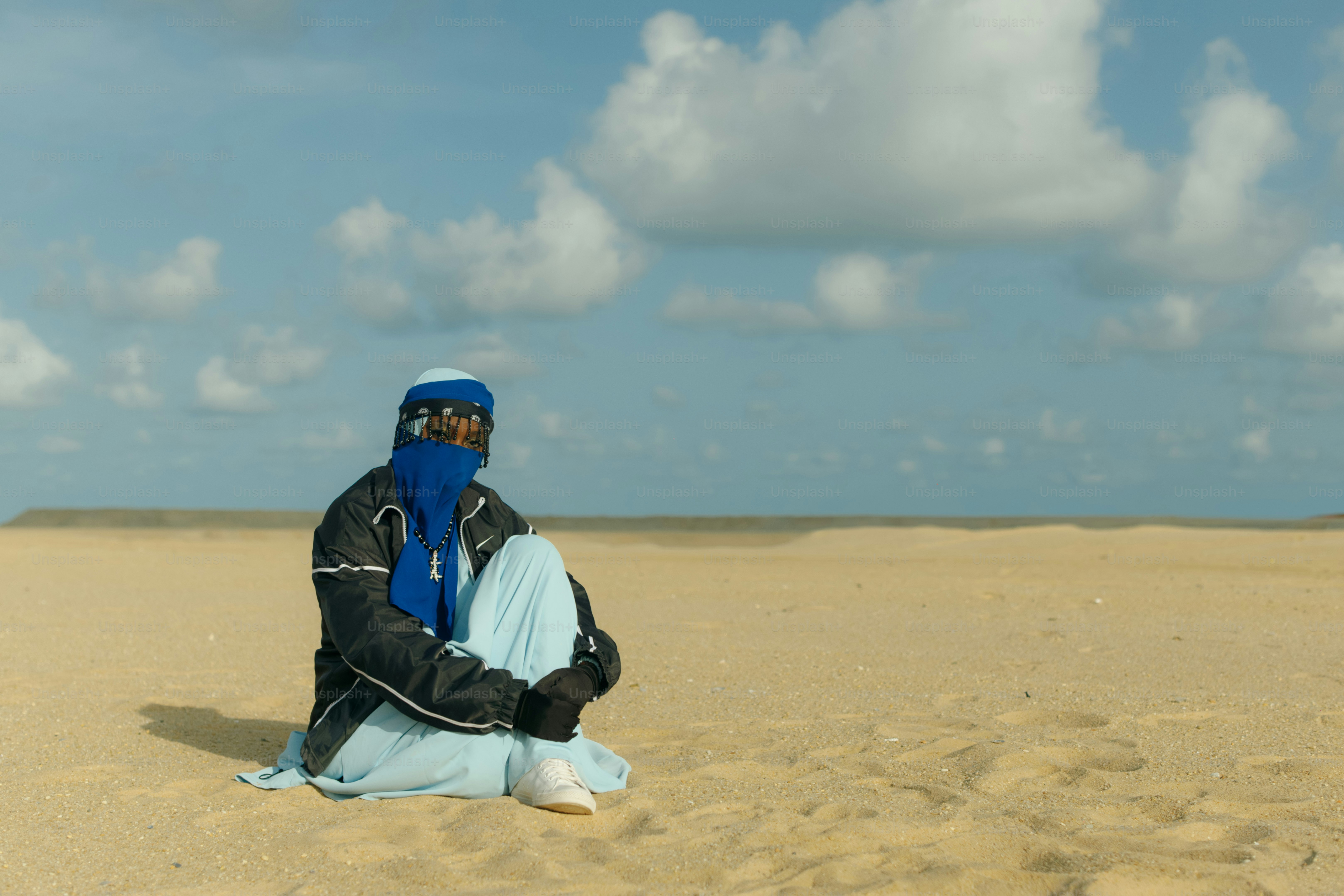 Persona en el desierto con pañuelo azul y cubrebocas.