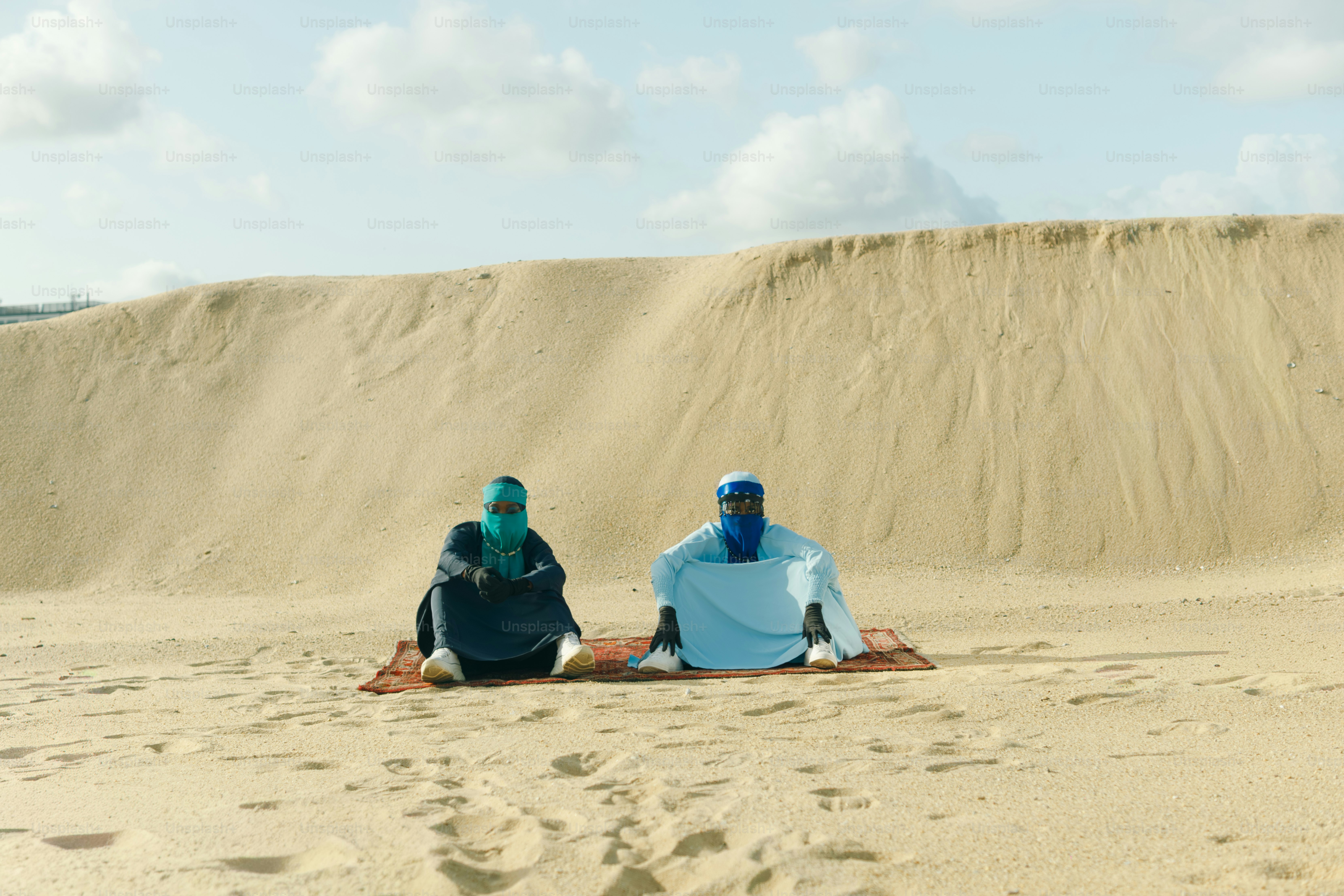 Deux personnes sont assises sur un tapis dans un vaste désert.