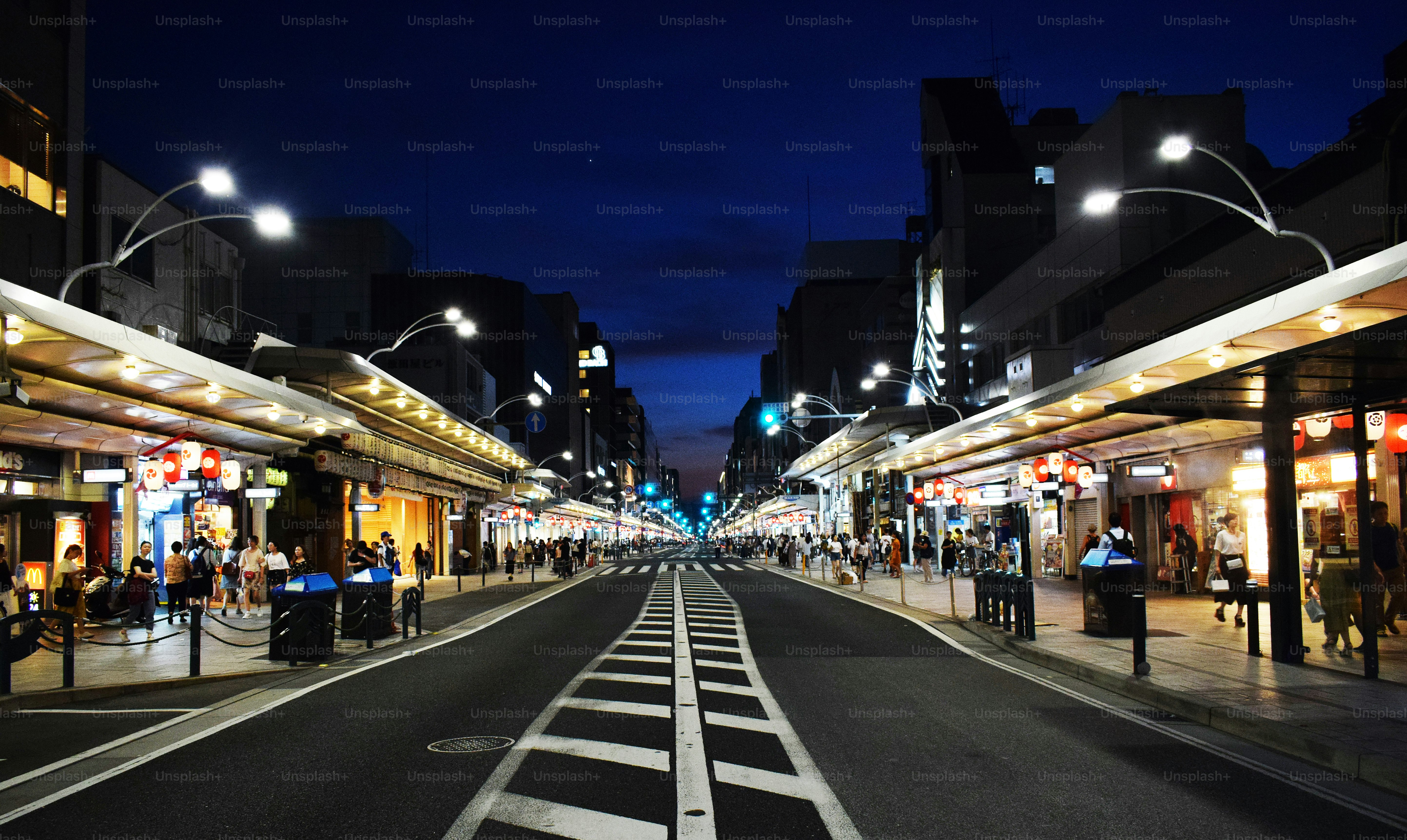 A bustling street scene at night with illuminated shops.