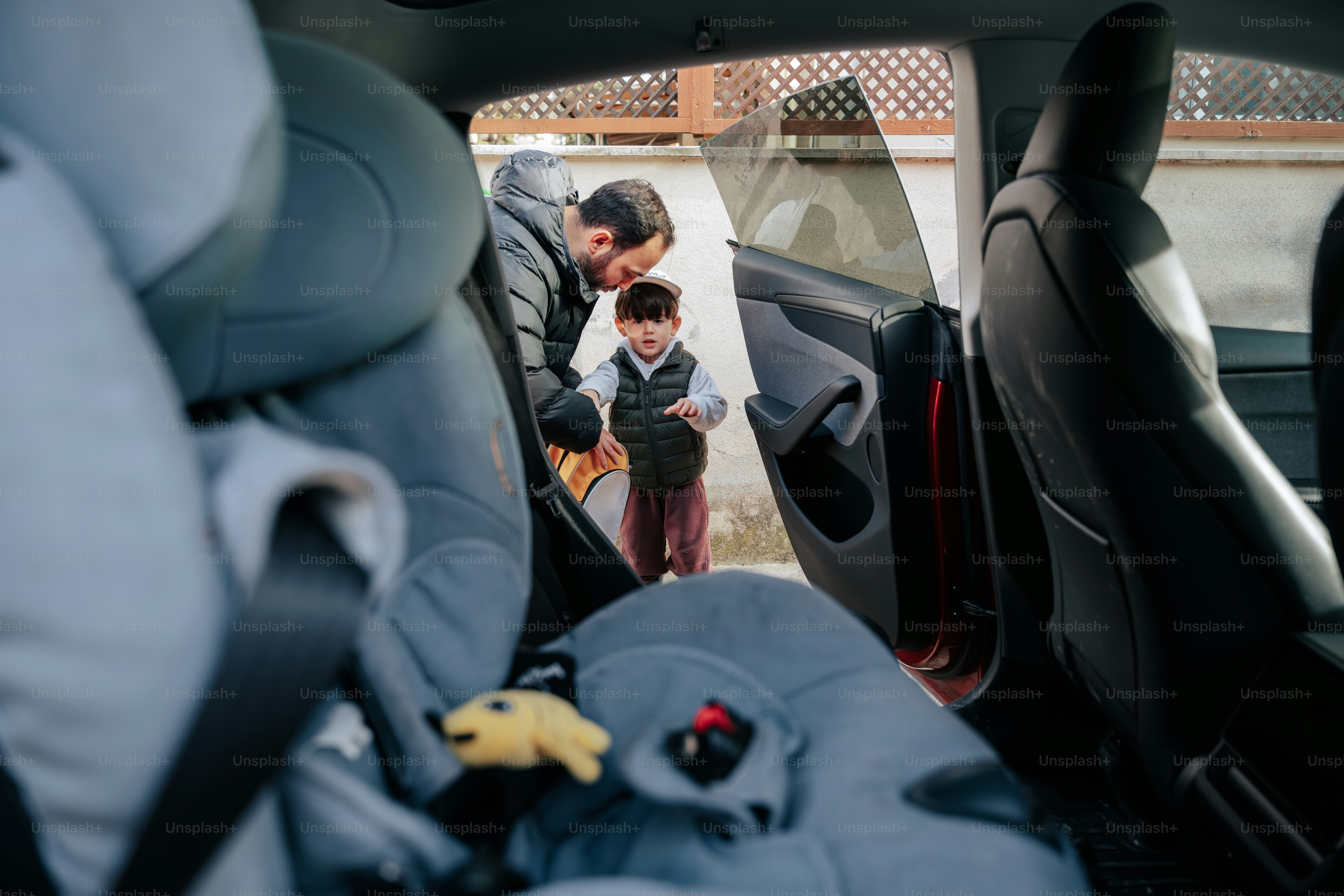 Ayah membantu anak duduk di kursi mobil di luar ruangan.